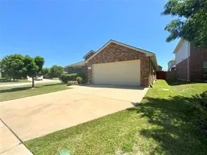 View of home's exterior featuring driveway, brick siding, a lawn, and a garage