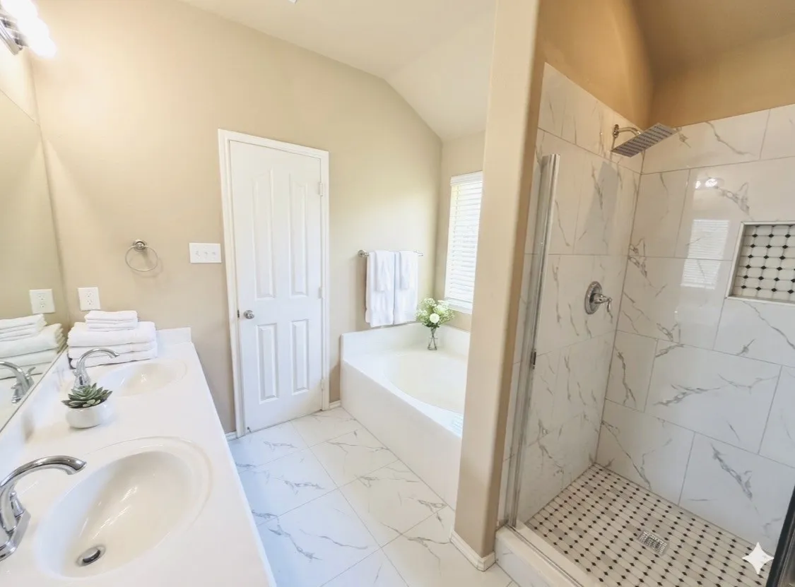 Bathroom featuring a dual vanity with undermount sinks, a soaking tub, and a separate glass-enclosed shower with a rainfall showerhead