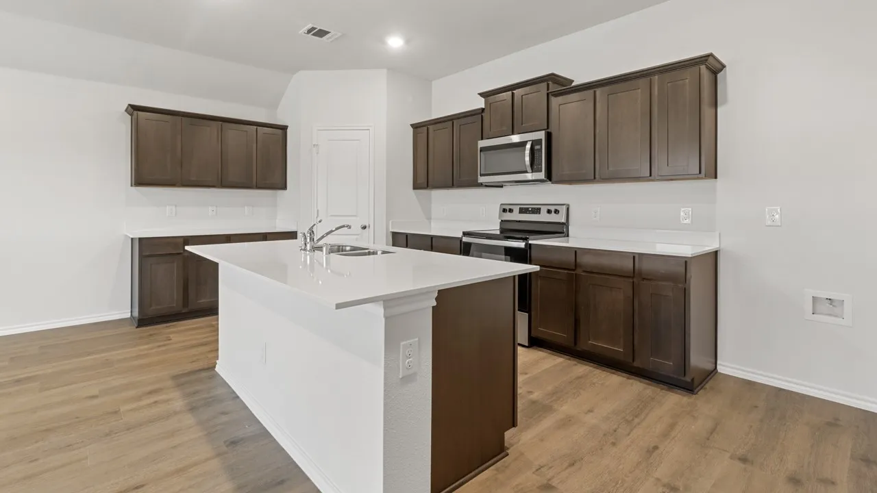 Modern kitchen featuring a central island with a double basin sink and a high-arc faucet, complemented by white countertops and dark wood cabinetry