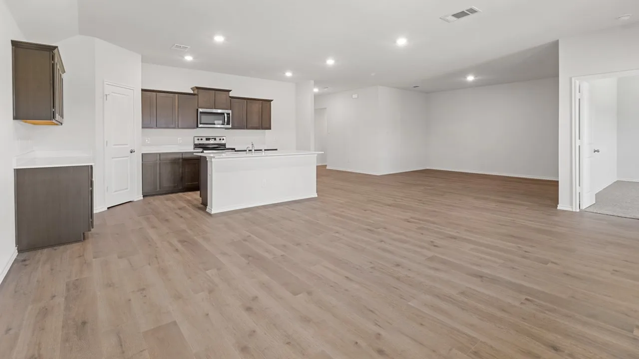 Open-concept living area featuring wood-finish flooring, recessed lighting, and a kitchen island with a double basin sink