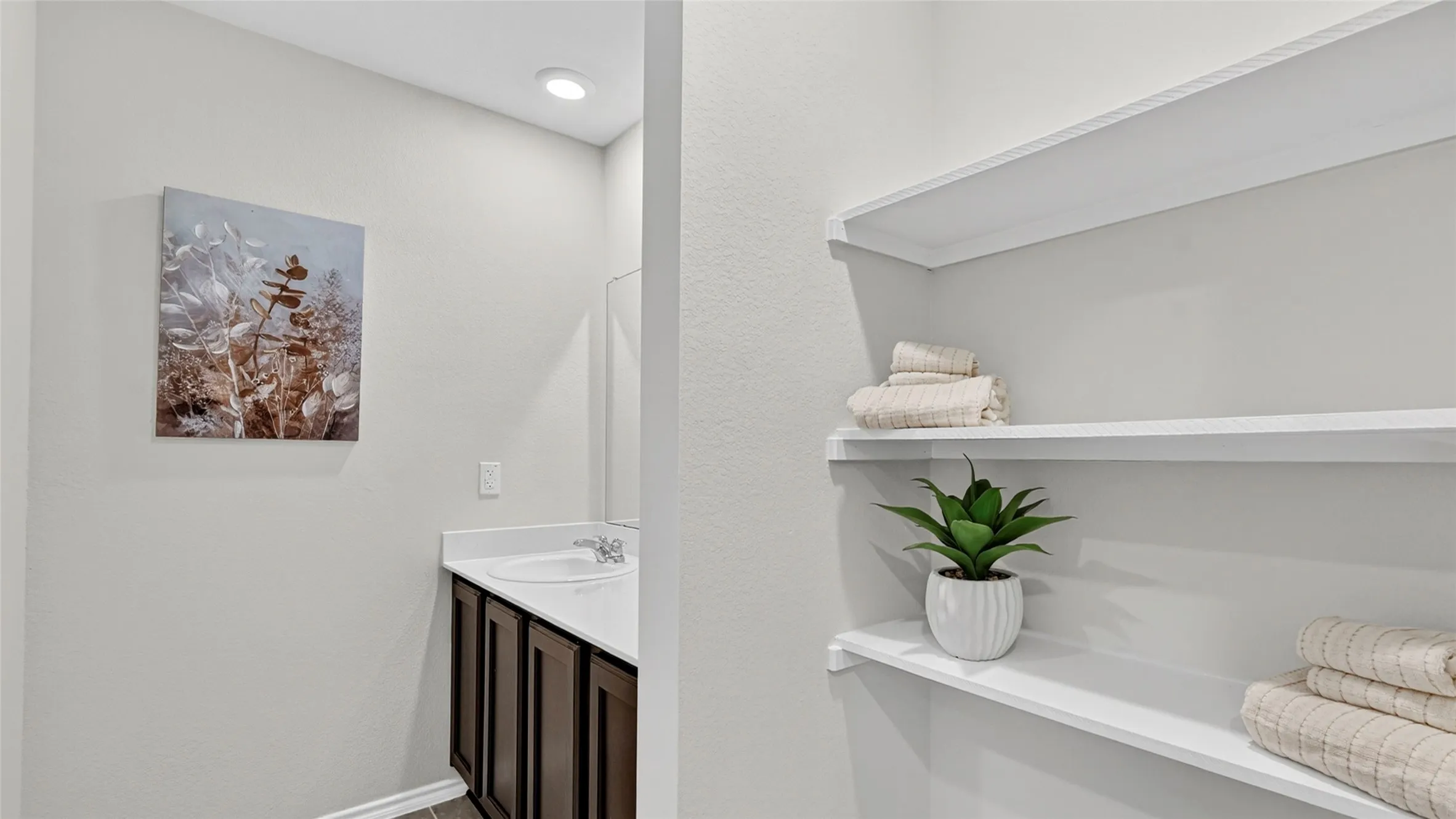Bathroom vanity with dark wood-finish cabinetry, a white countertop, and an undermount sink