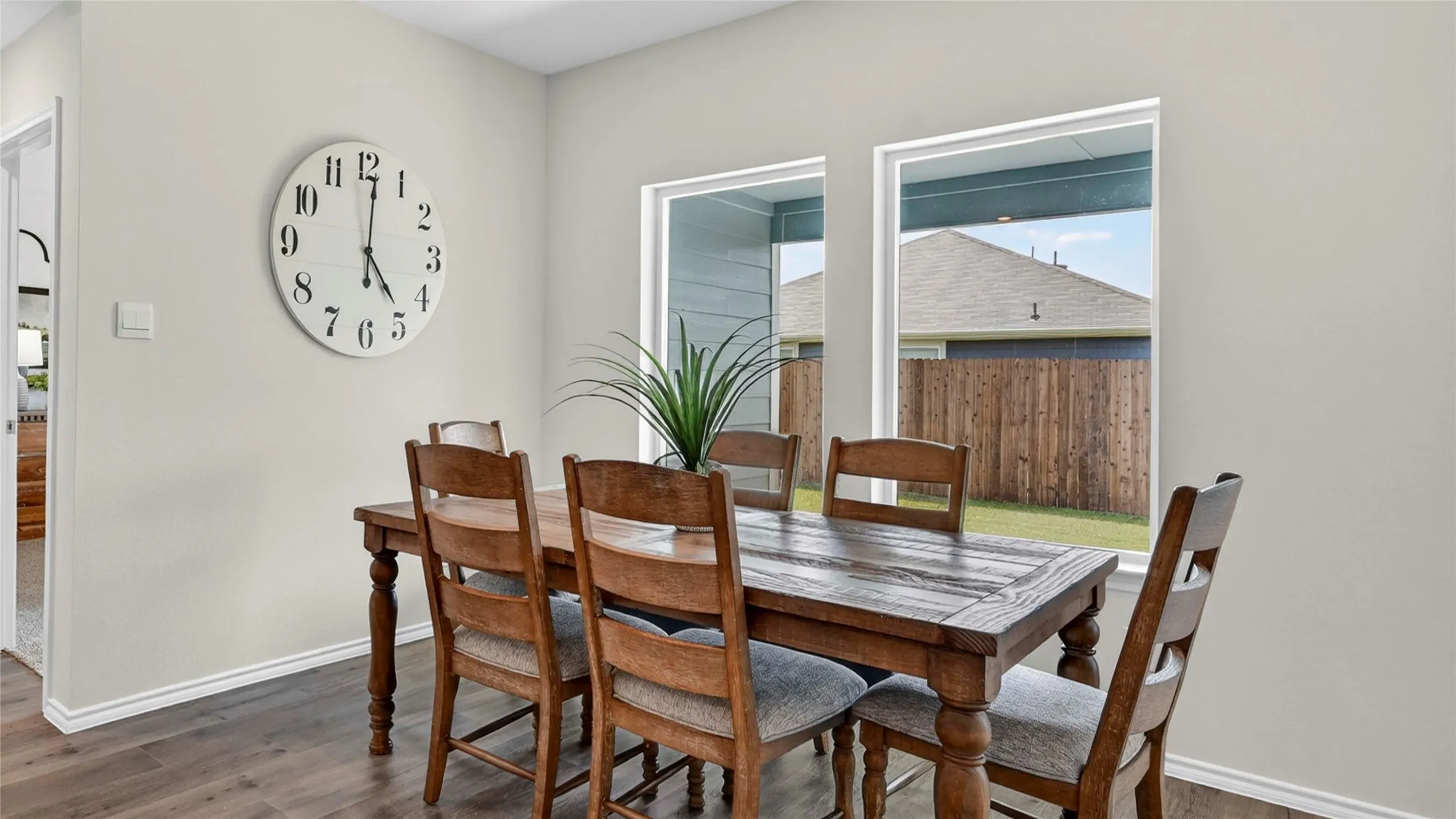 Bright room featuring wood-finish flooring, two large windows, light gray wall paint, and white baseboards