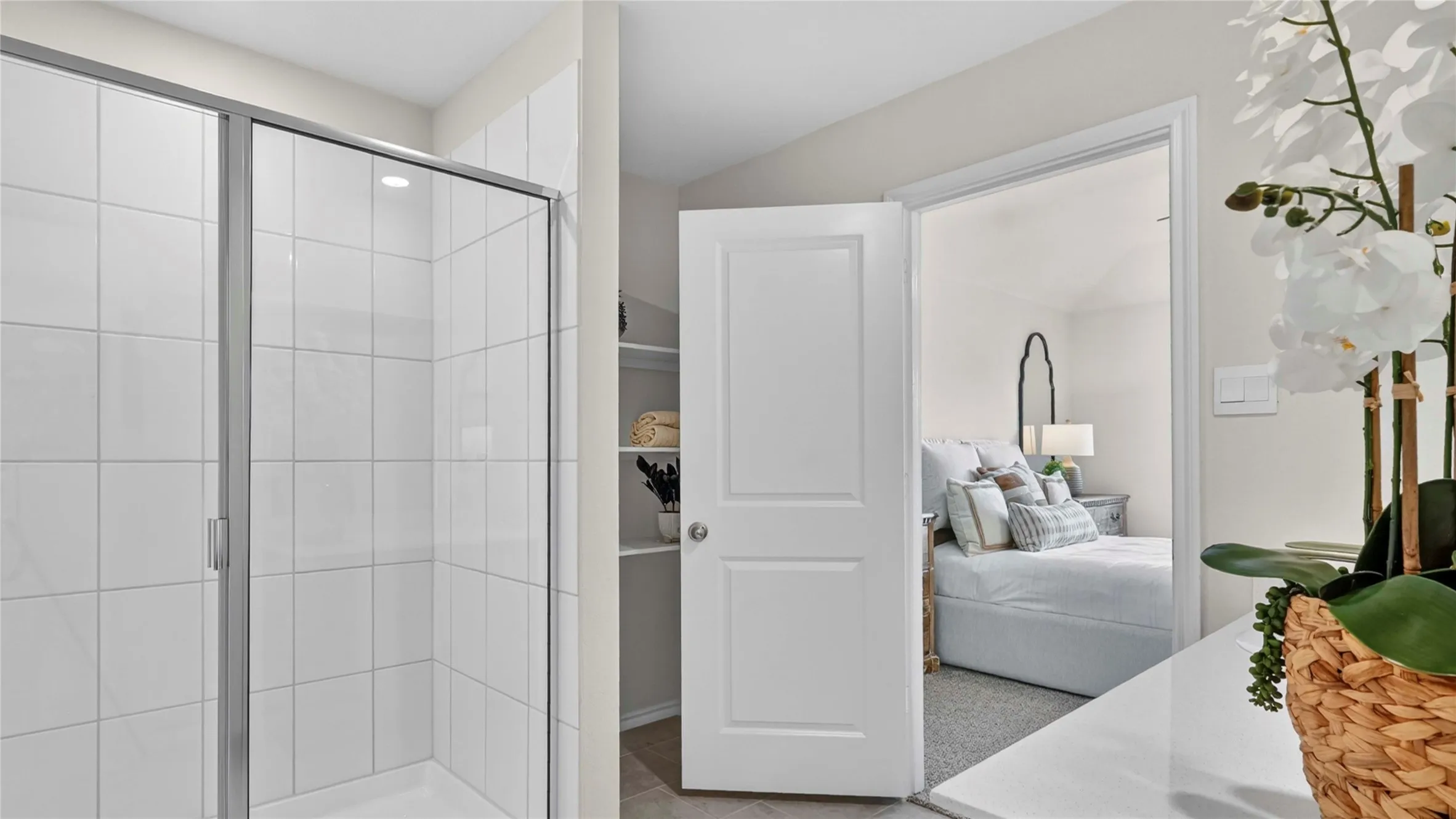 Glass-enclosed shower with white subway tile surround, featuring a built-in shelf alcove