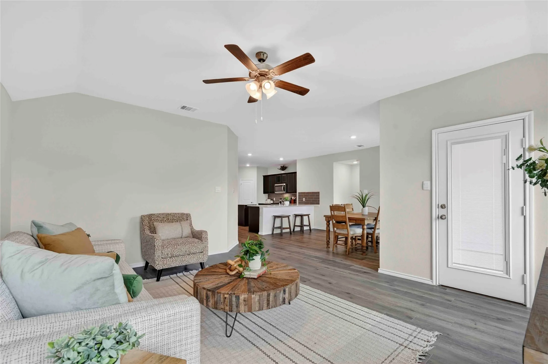 Open concept living area featuring wood-finish flooring, vaulted ceilings, and a ceiling fan with integrated​​‌​​​​‌​​‌‌​‌‌​​​‌‌​‌​‌​‌​​​‌​​ lighting
