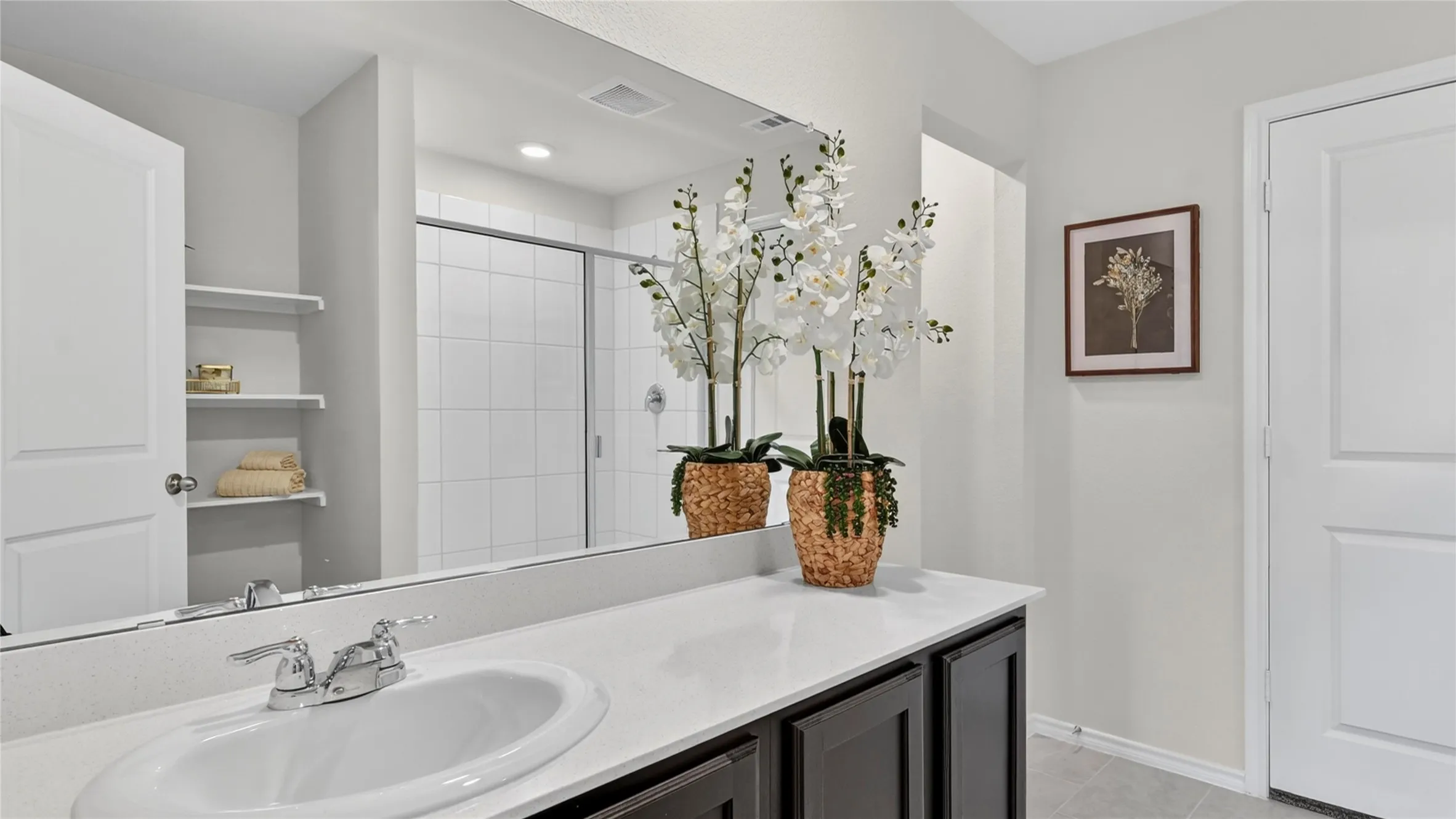 Bathroom vanity featuring a single oval sink, chrome-finish faucet, and a light-toned countertop