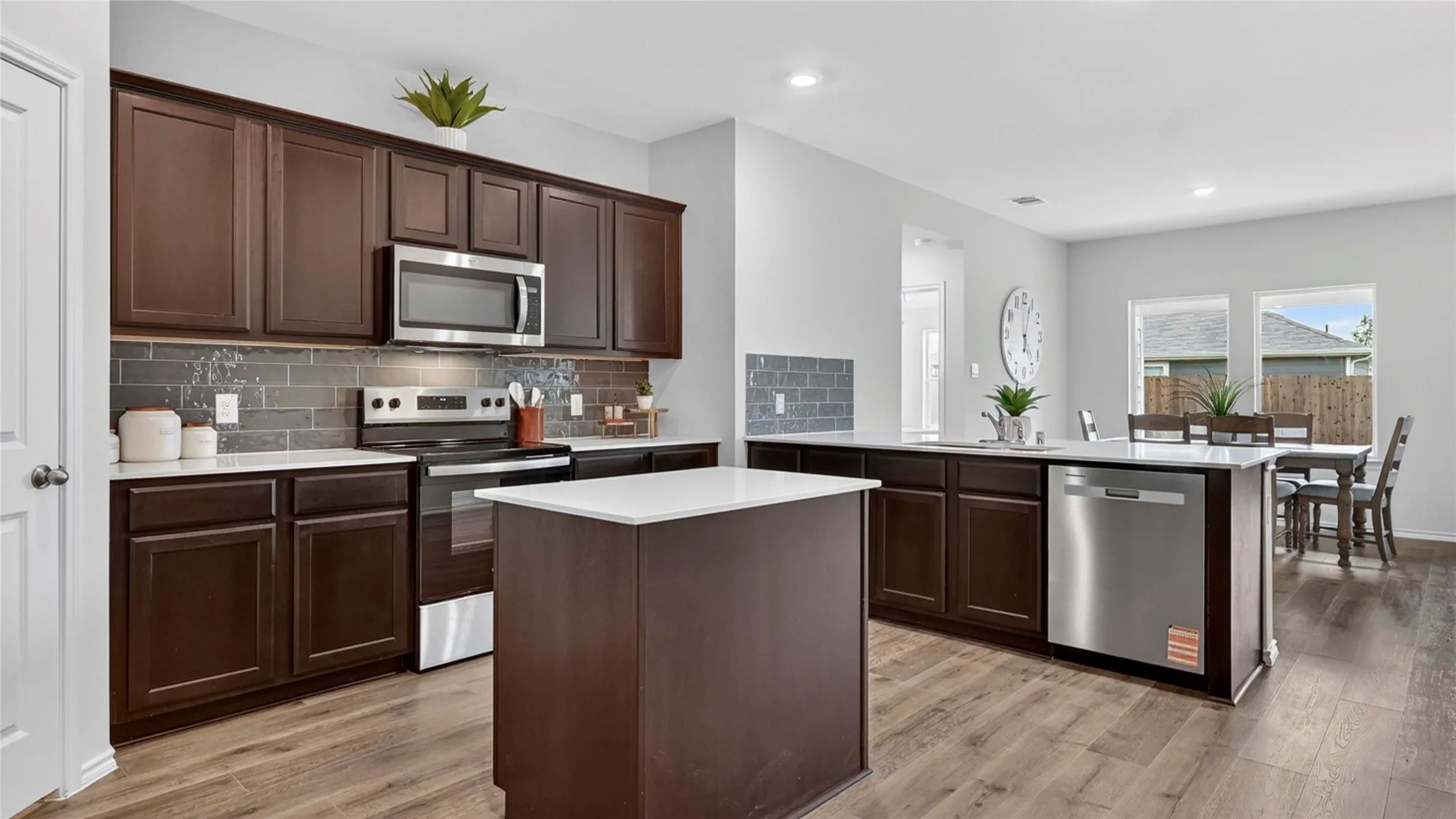 Kitchen featuring dark wood cabinetry, stainless steel appliances, a center island with a white countertop, and wood-finish flooring