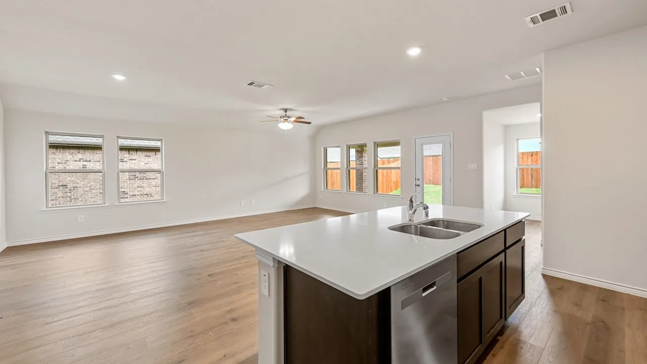 Open-concept living area featuring an island kitchen with a double basin sink and stainless steel dishwasher