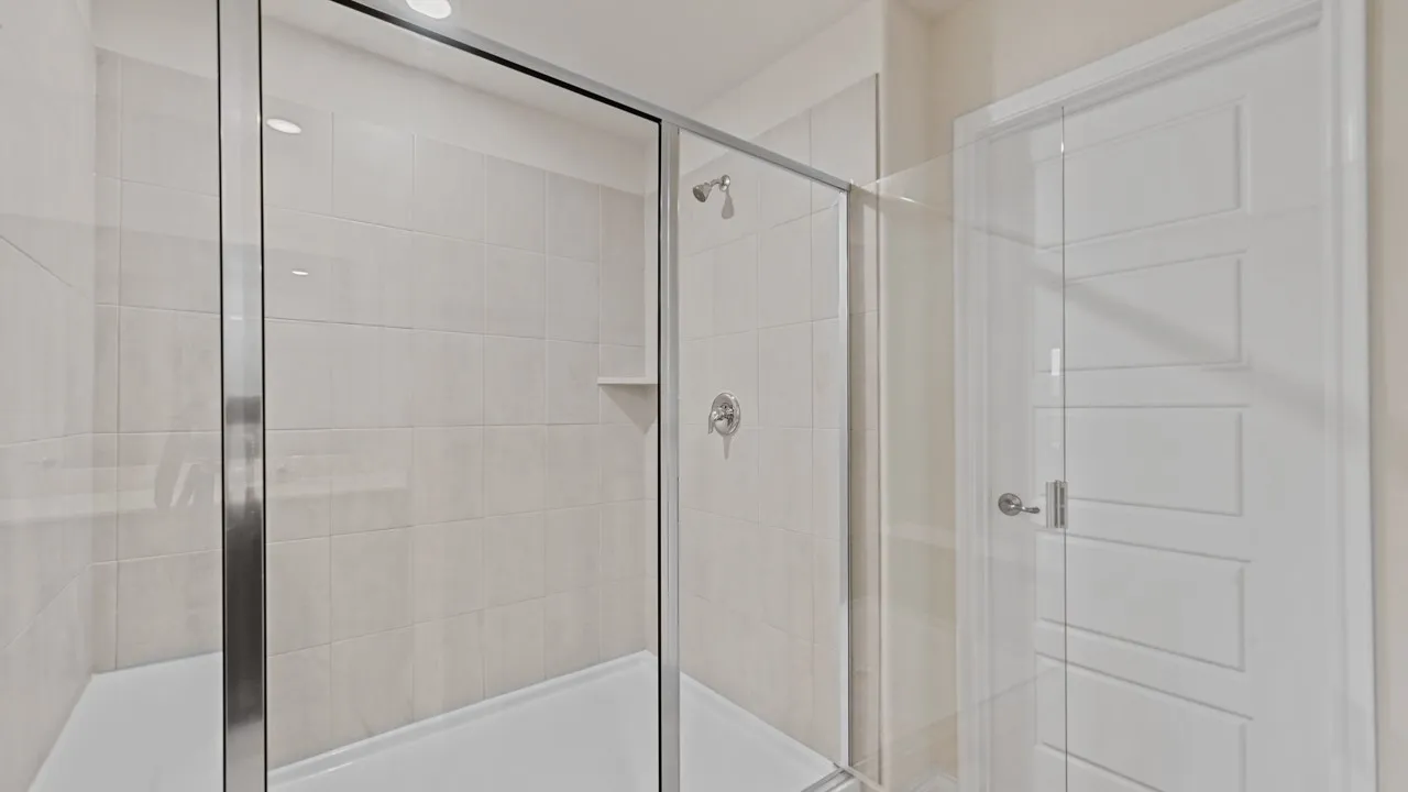 Glass-enclosed shower with subway tile surround, built-in shelving, and a chrome showerhead