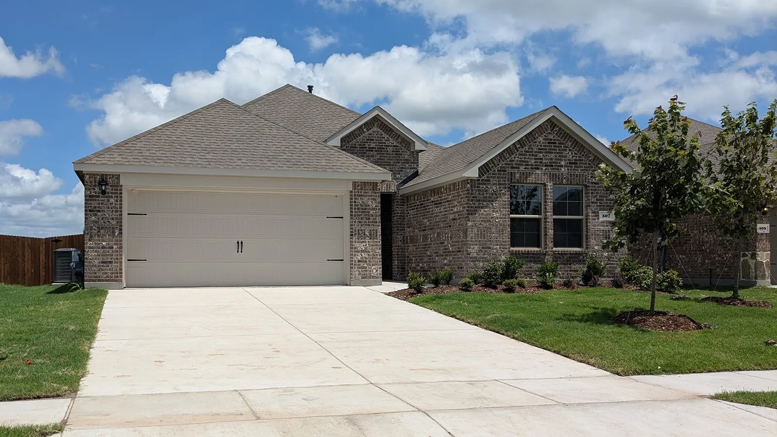 Brick exterior with a gabled roofline, two-car garage, concrete driveway, and front landscaping