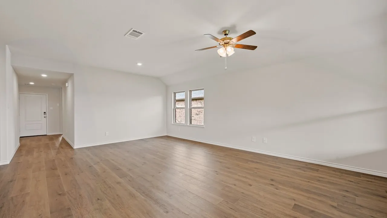 Spacious interior room featuring wood-finish flooring, recessed lighting, and a ceiling fan with light fixture