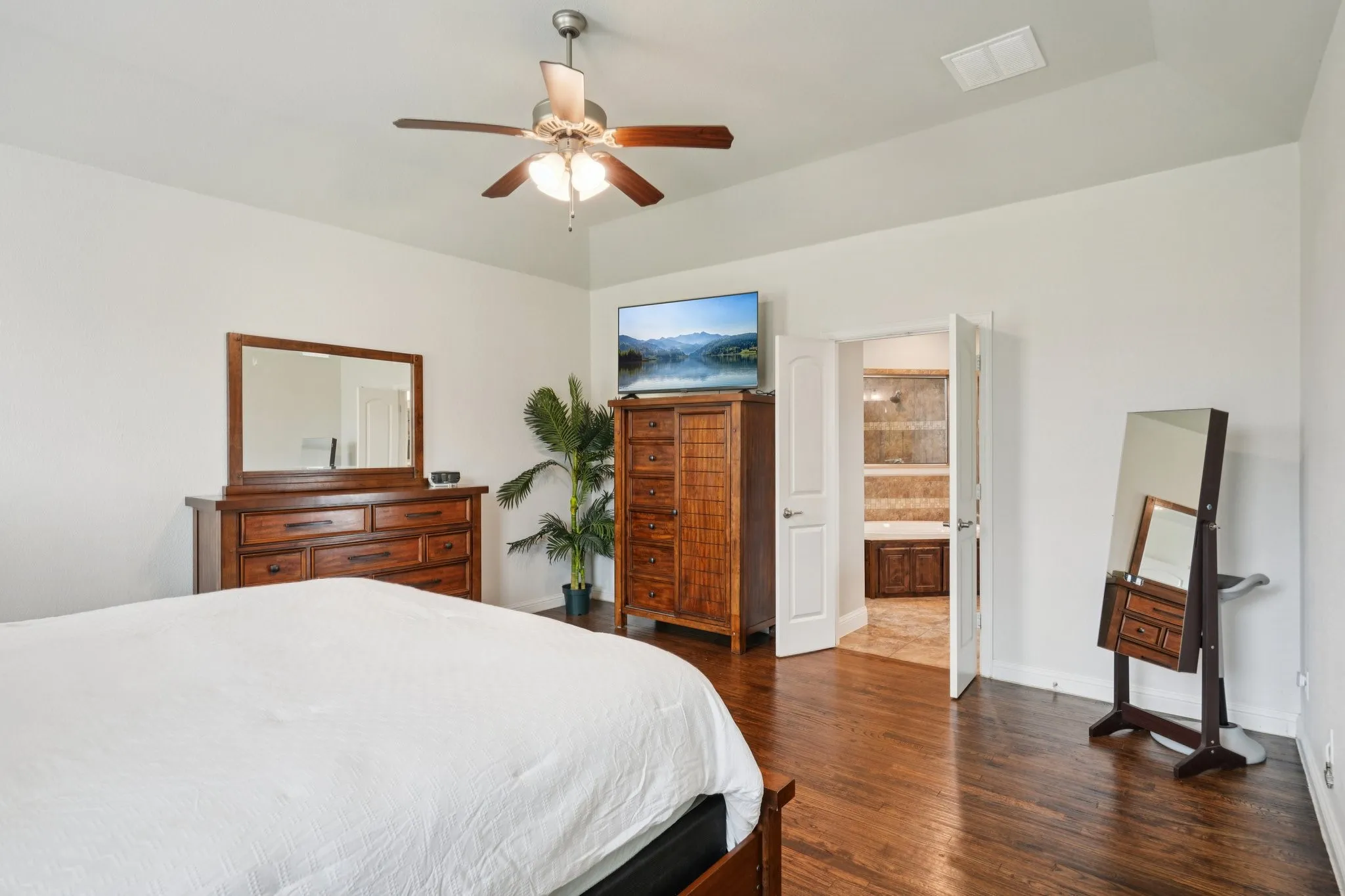 Primary bedroom featuring wood floors and abundant natural light from large windows.