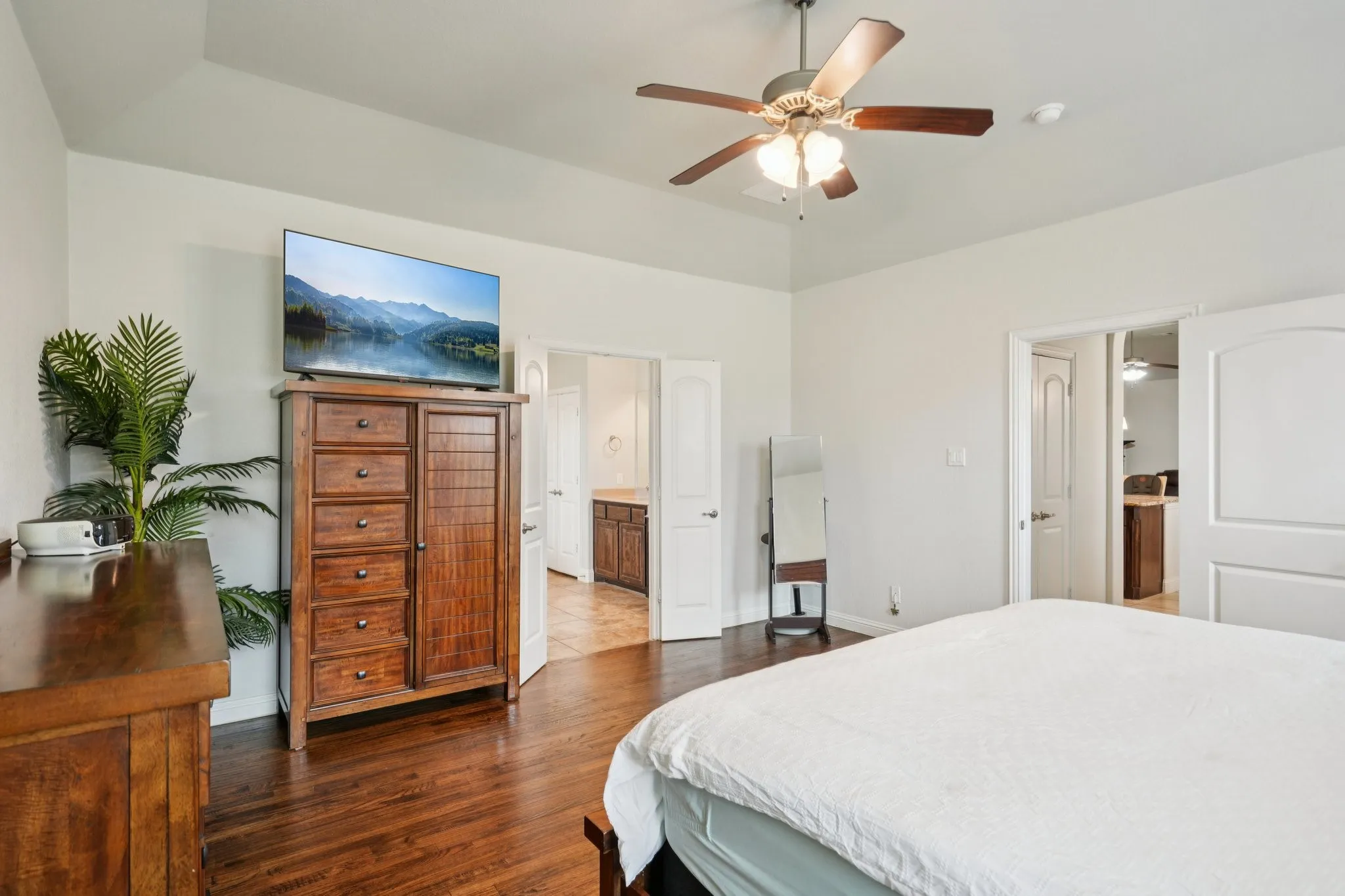 Primary bedroom featuring wood floors and abundant natural light from large windows.
