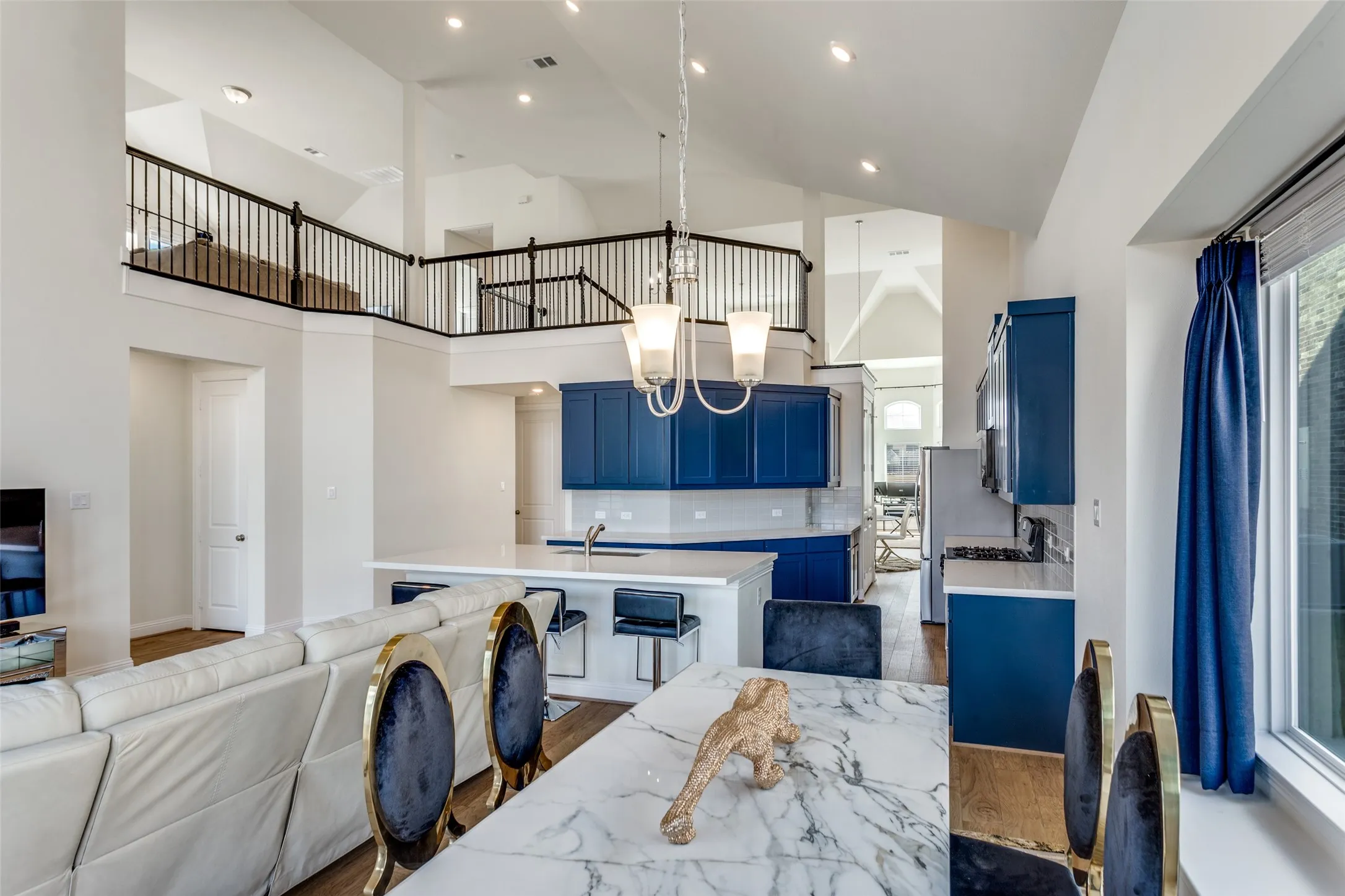 Kitchen featuring blue cabinetry, open floor plan, an island with sink, dark wood-style floors, and a chandelier