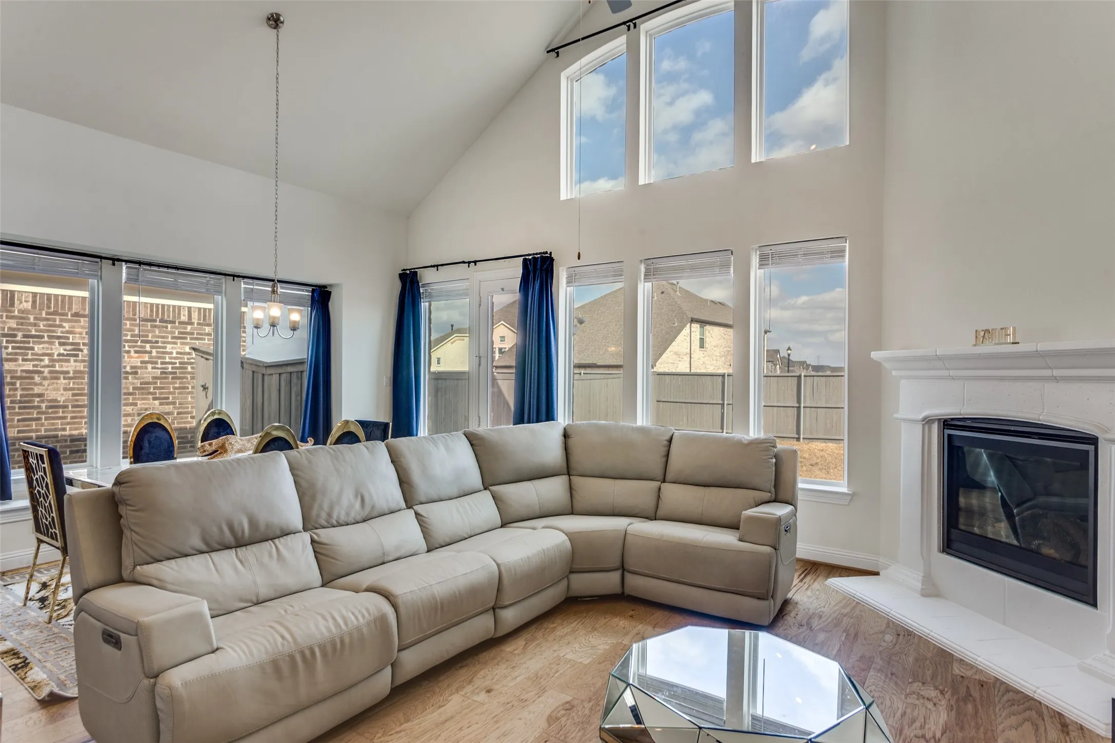 Living area with a glass covered fireplace, lofted ceiling, hanging lights, and wood finished floors