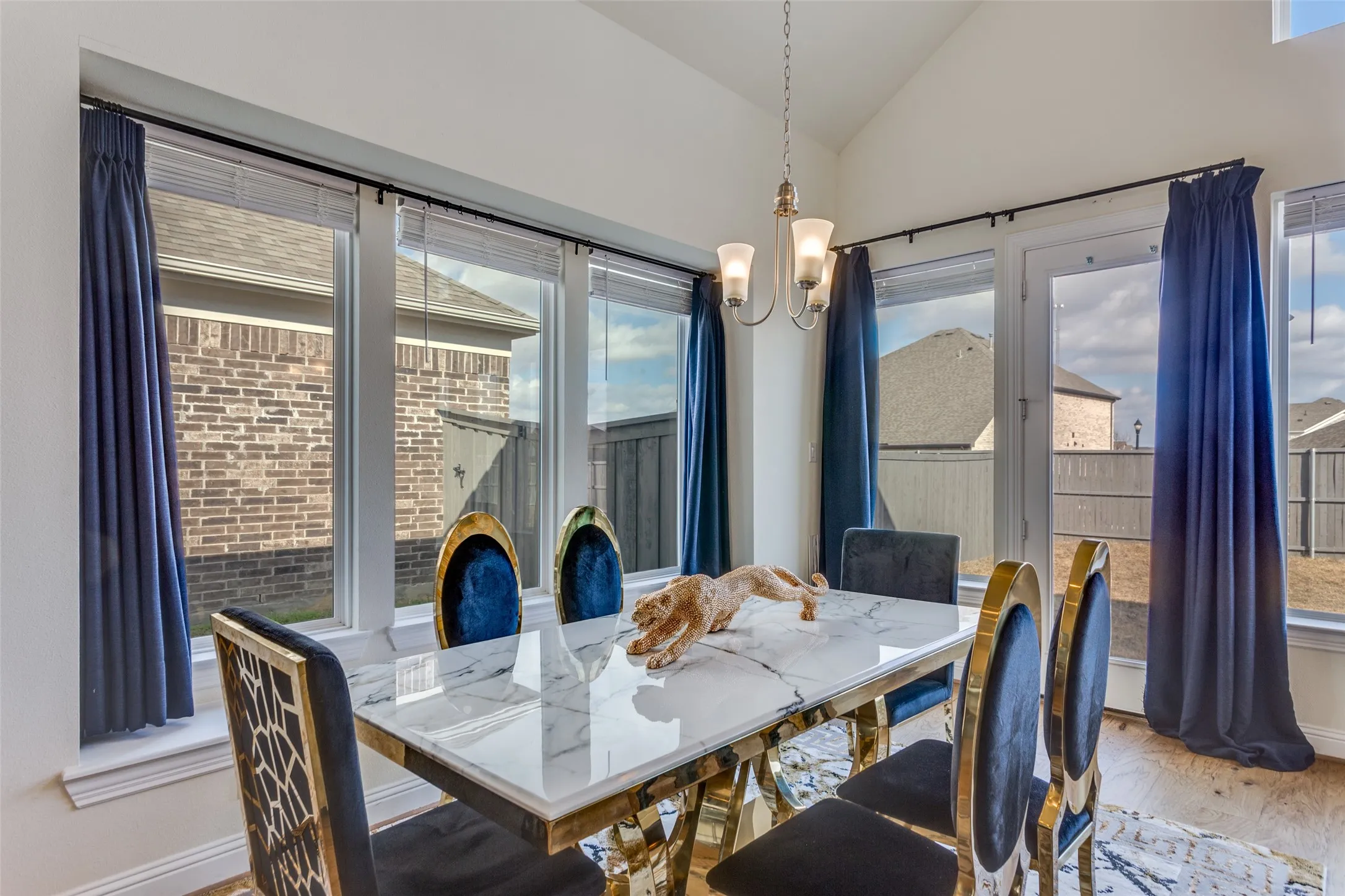 Dining space with lofted ceiling, light wood finished floors, suspended lighting, and plenty of natural light