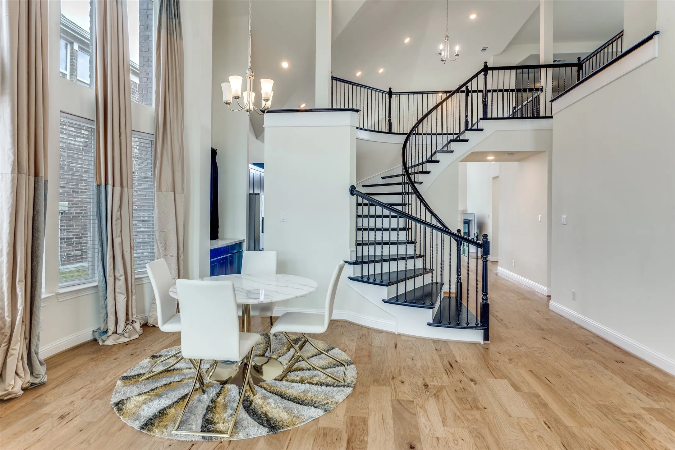 Dining room with suspended lighting, light wood-style flooring, and a high ceiling