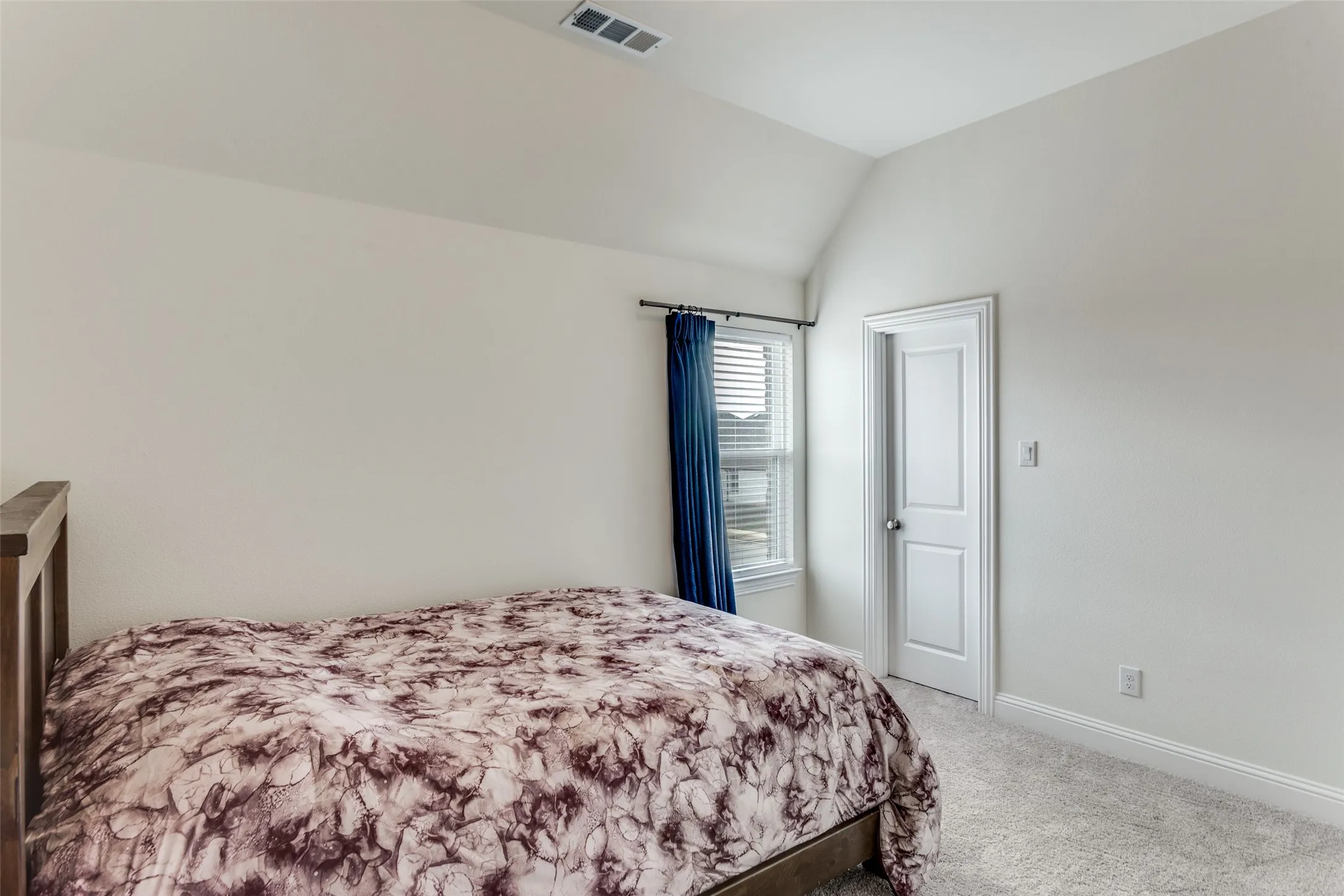 Bedroom with light colored carpet and vaulted ceiling