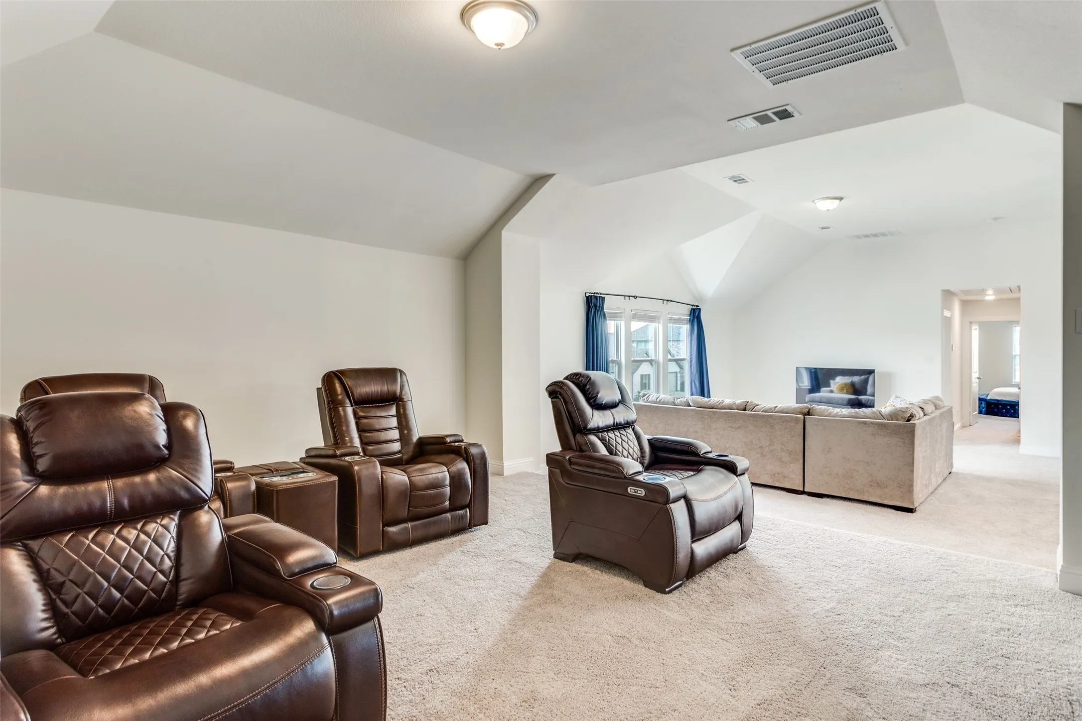 Home theater featuring carpet flooring and vaulted ceiling