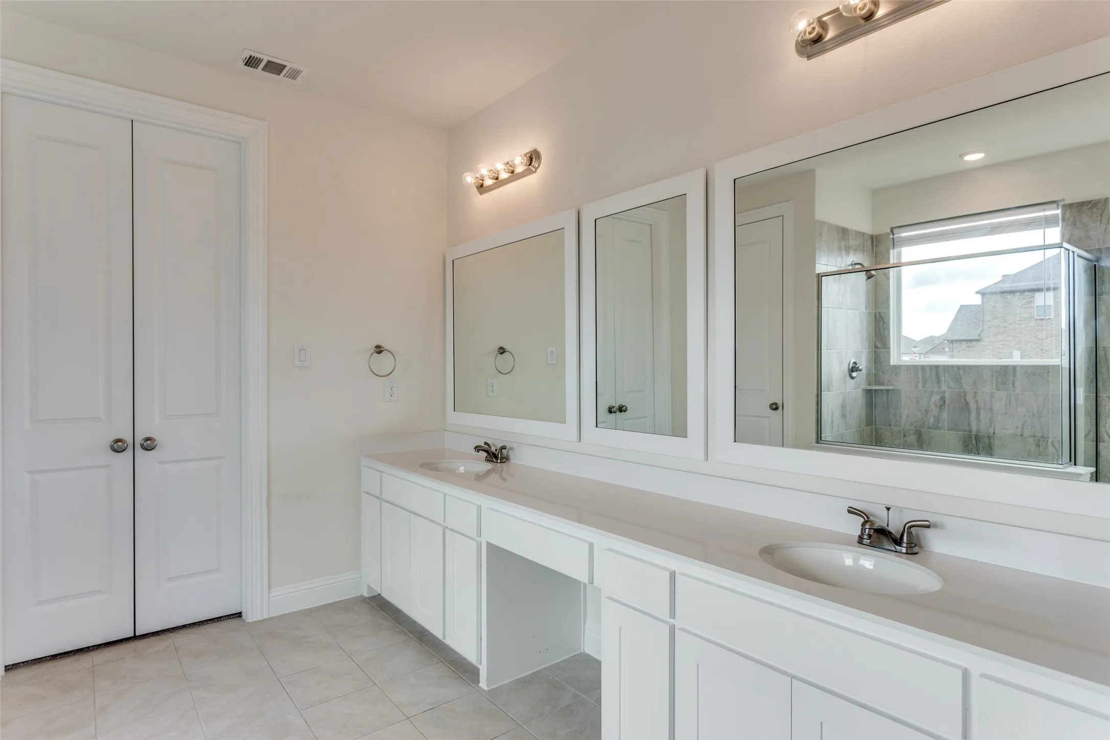 Full bathroom with double vanity, a closet, a shower stall, and light tile patterned floors