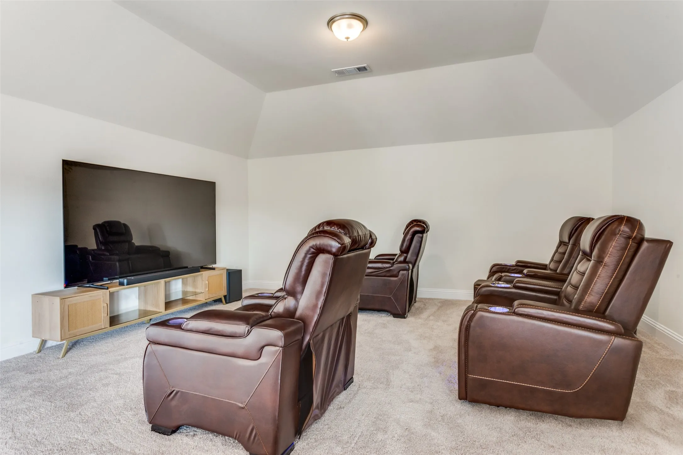 Home theater room featuring light colored carpet and vaulted ceiling