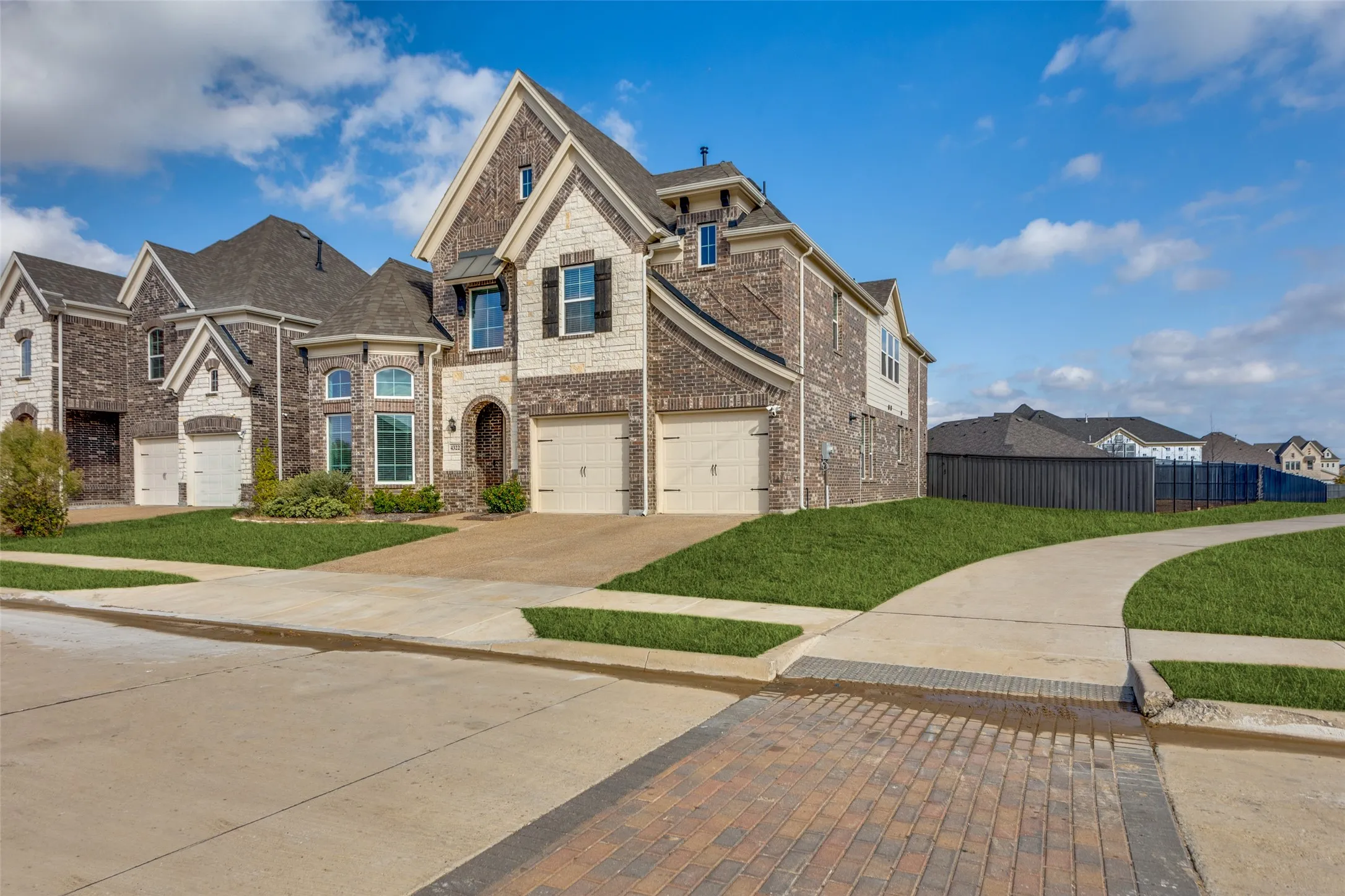 French provincial home featuring a residential view, concrete driveway, a garage, brick siding, and stone siding