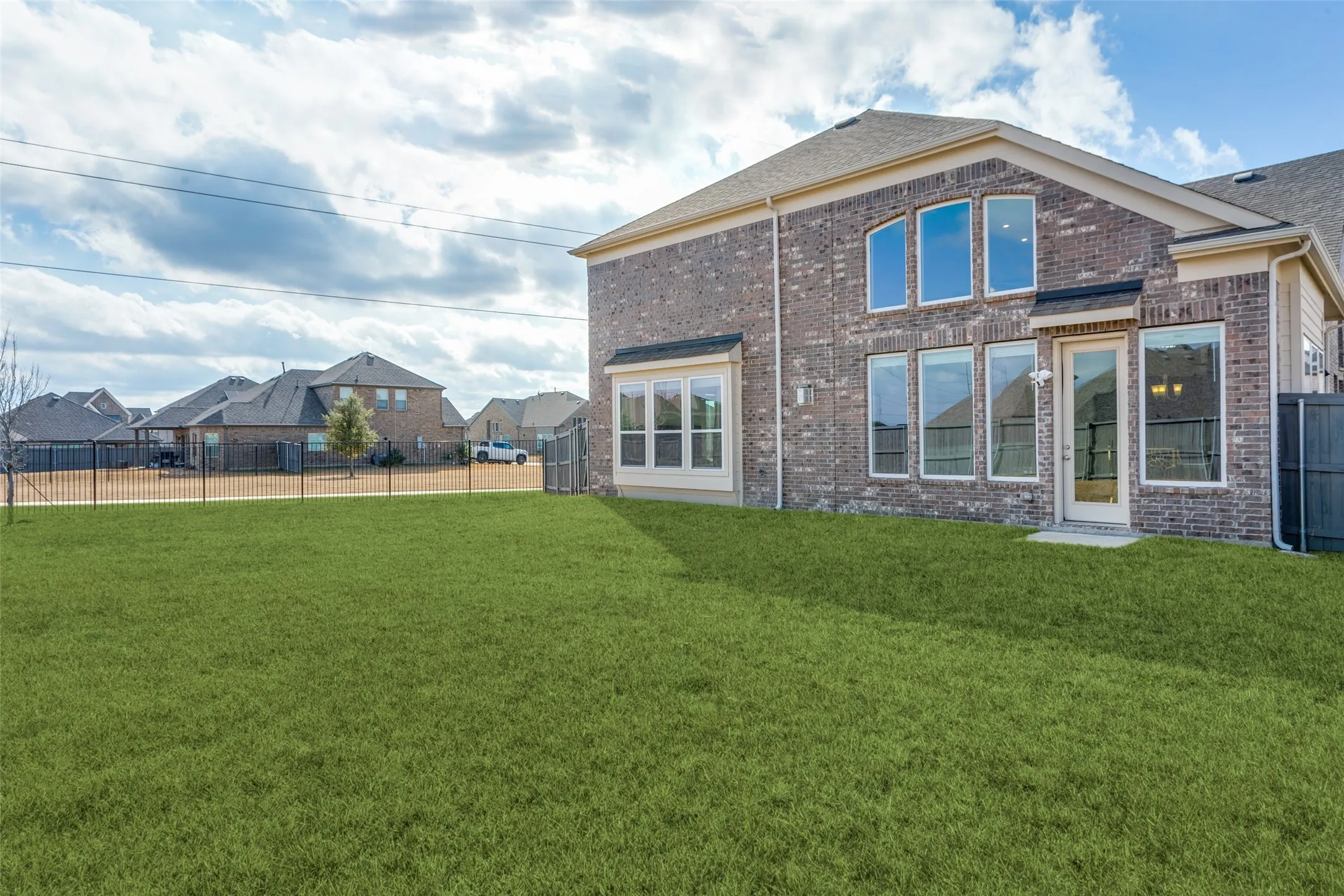 Back of property with brick siding and a fenced backyard