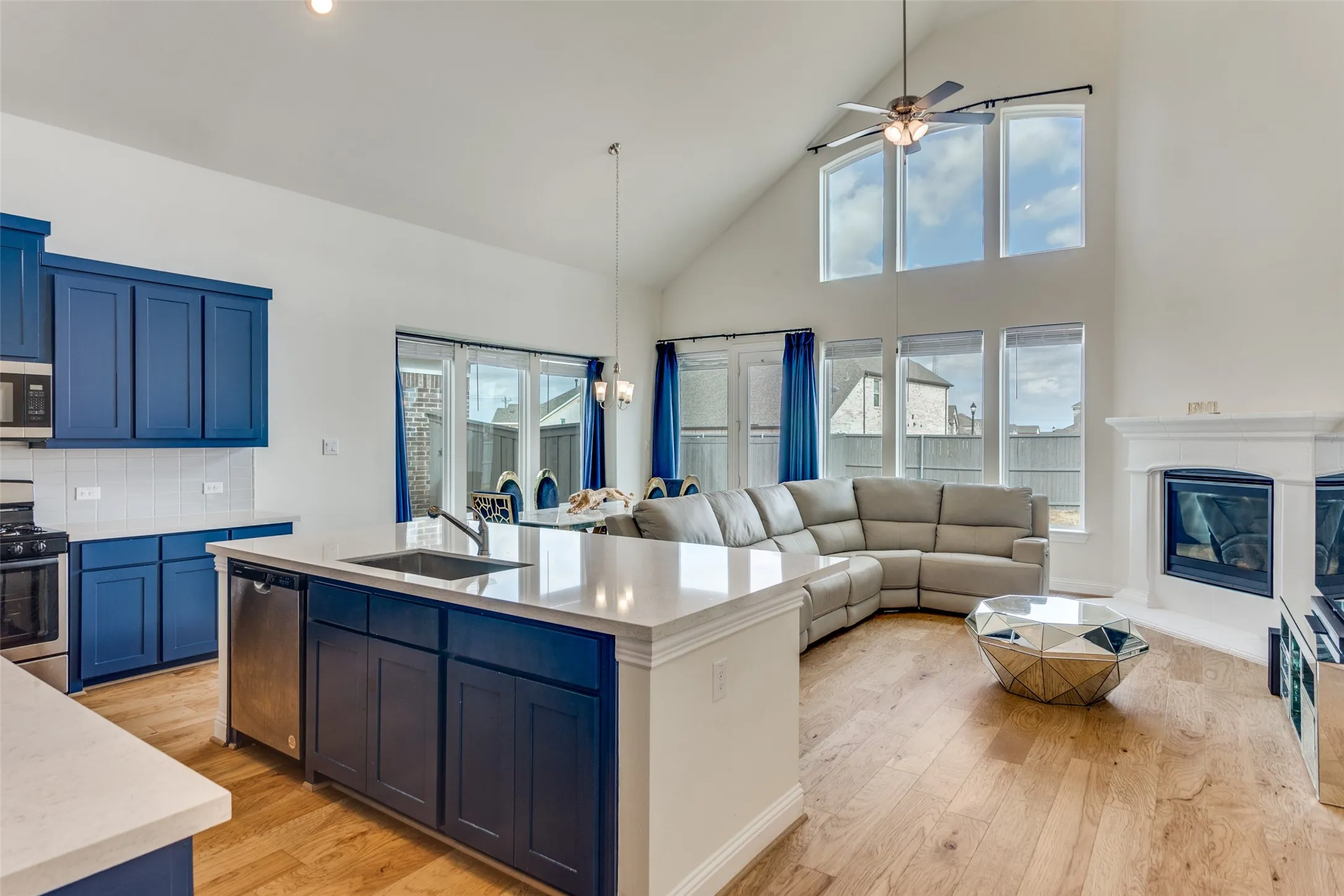 Kitchen featuring light wood-style flooring, stainless steel appliances, a center island with sink, open floor plan, and vaulted ceiling