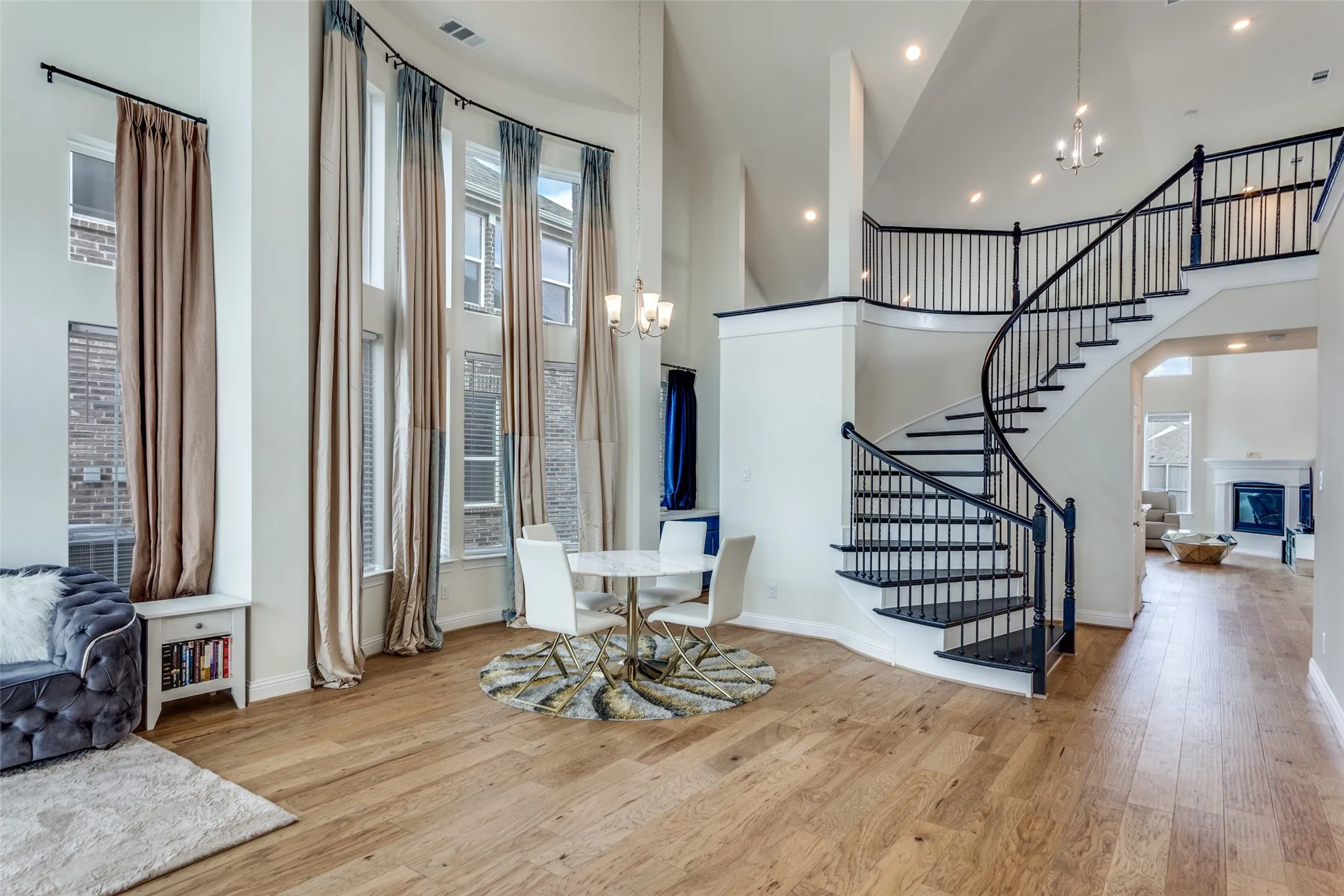 Entryway with hanging lights, a glass covered fireplace, a high ceiling, light wood finished floors, and healthy amount of natural light