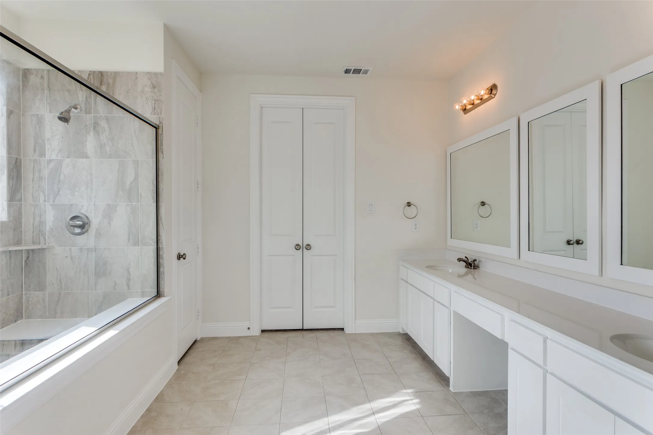 Full bathroom with double vanity, light tile patterned floors, and a closet