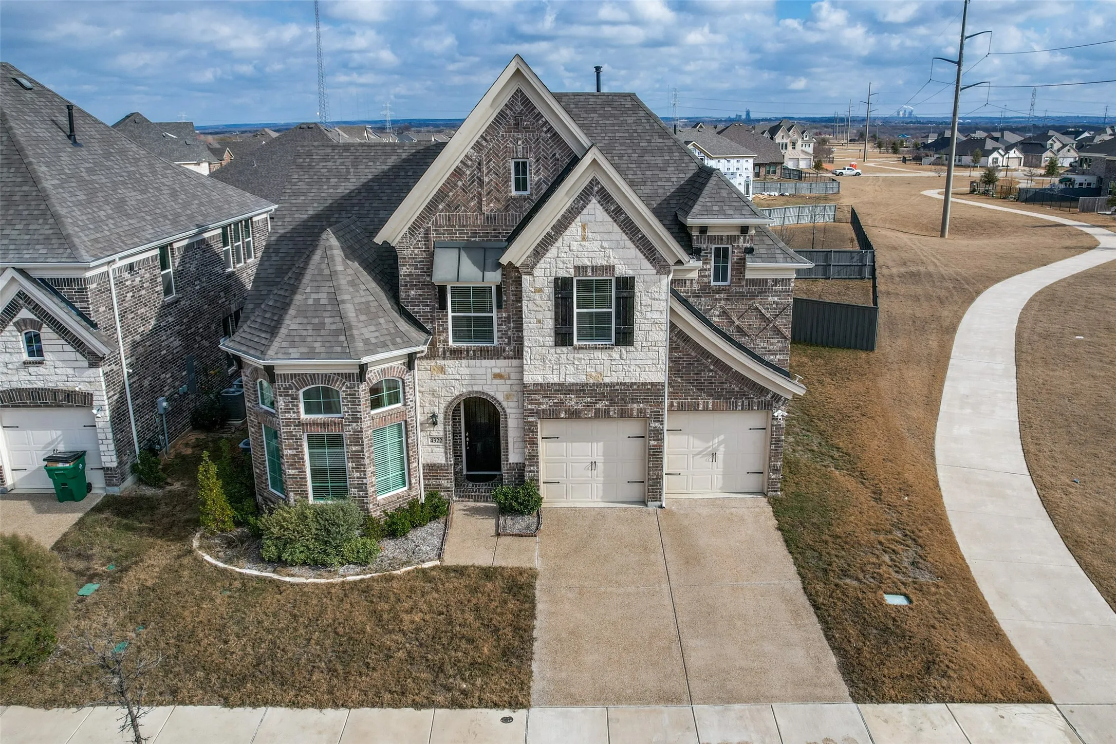 French country home with stone siding, a residential view, driveway, a shingled roof, and an attached garage