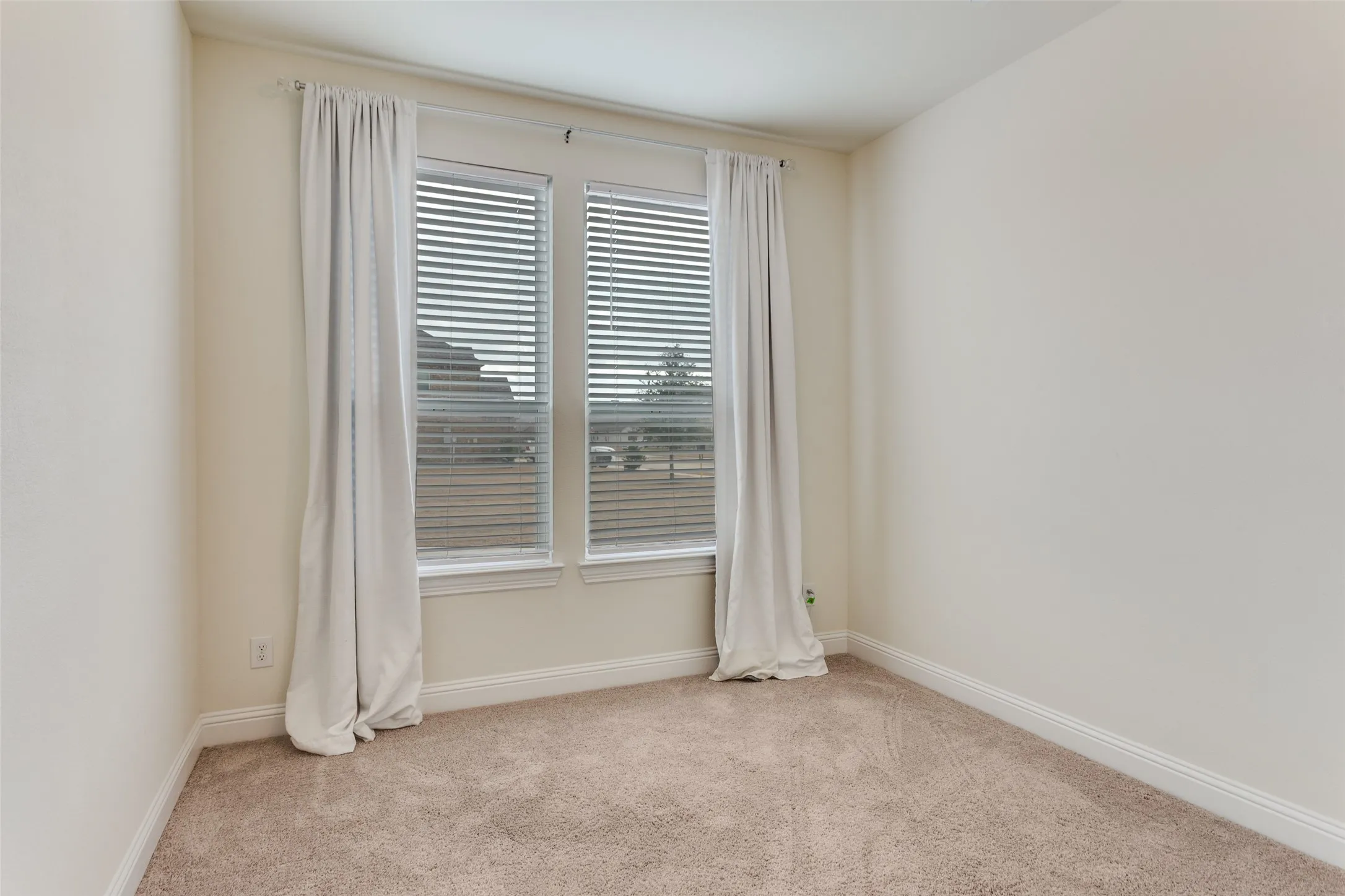 Empty room featuring light colored carpet and baseboards