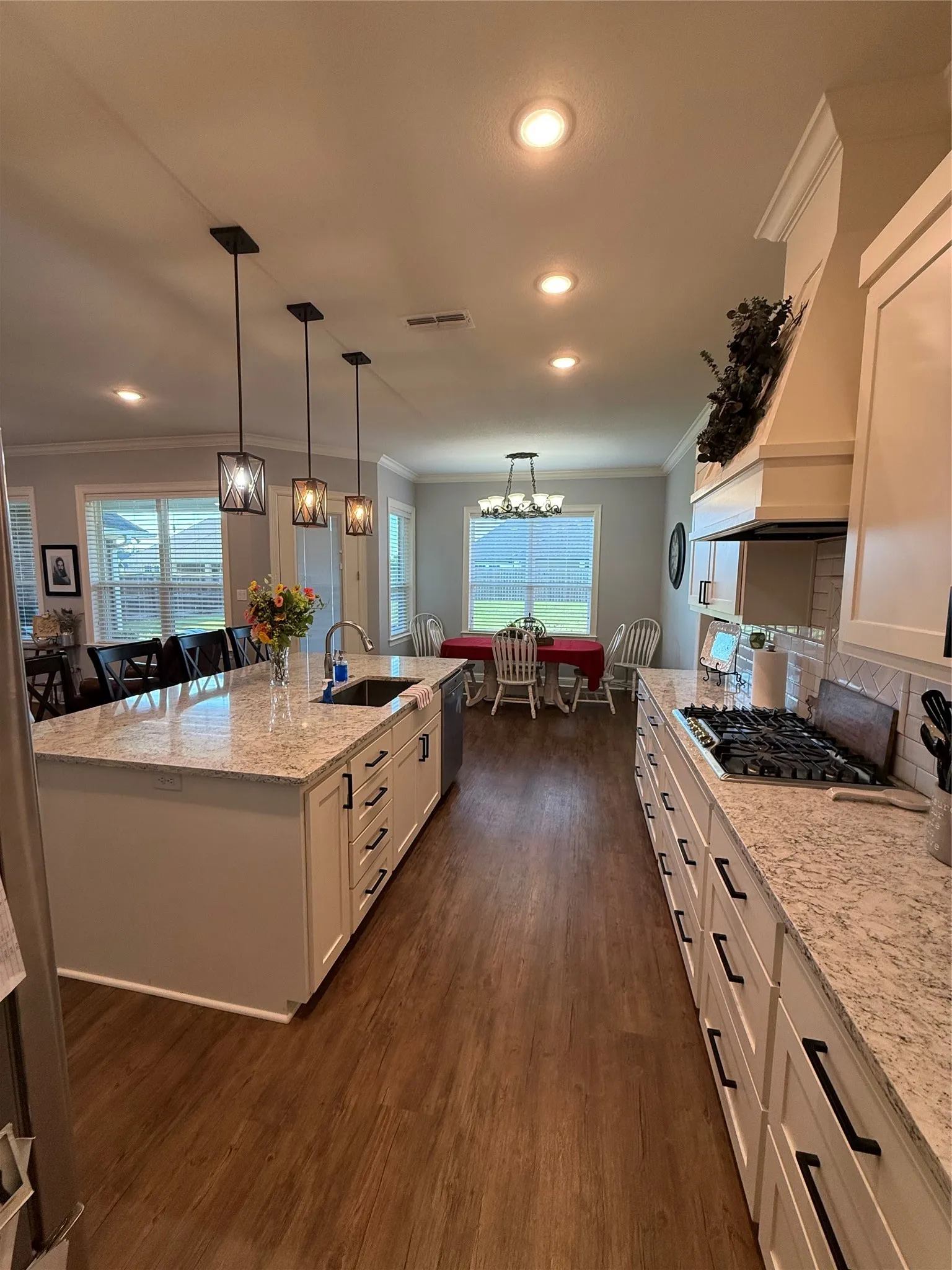 Kitchen featuring a sink, ornamental molding, white cabinetry, dark wood-style flooring, and light stone counters