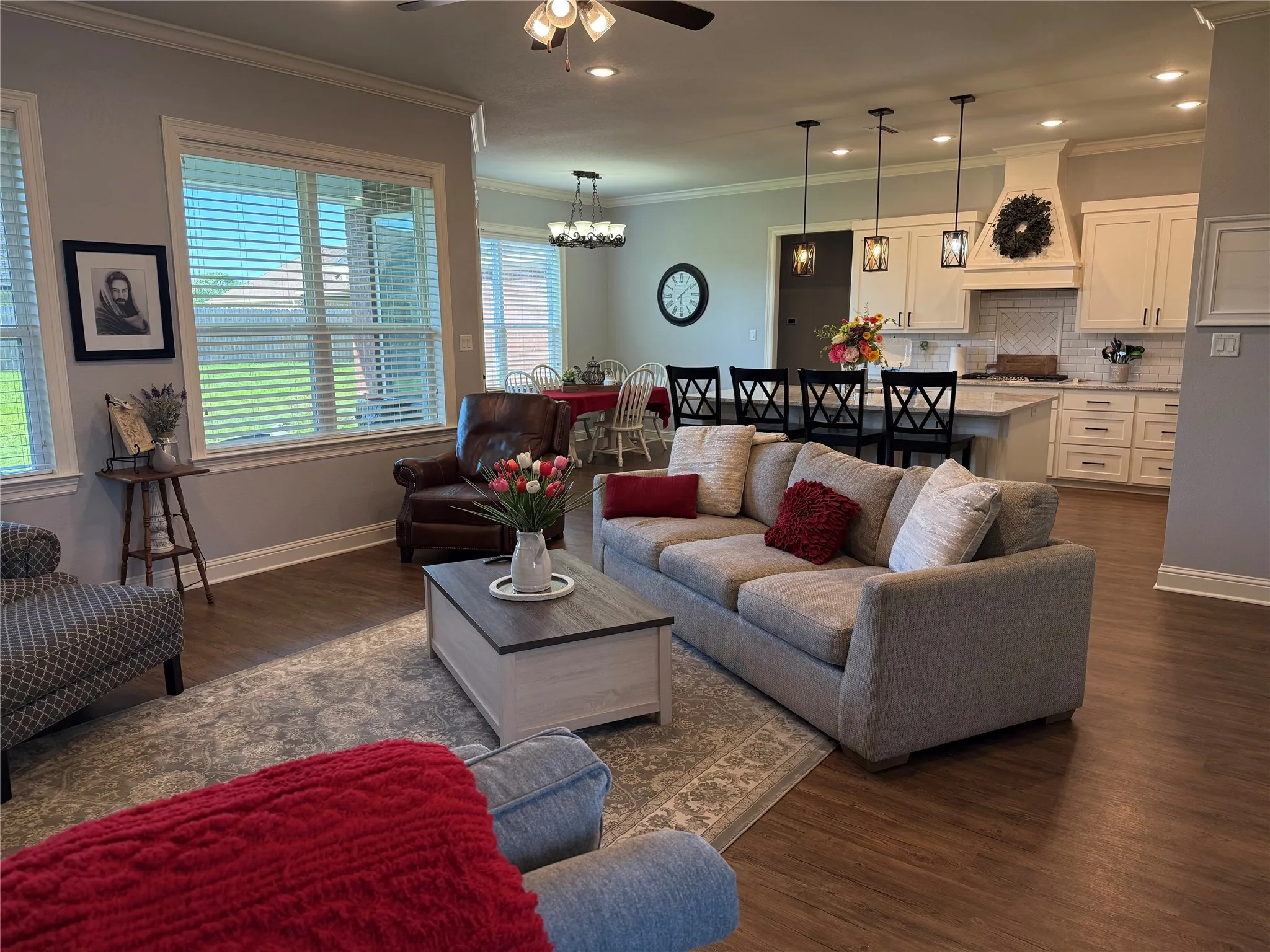 Living room with a ceiling fan, dark wood-style flooring, healthy amount of natural light, baseboards, and crown molding