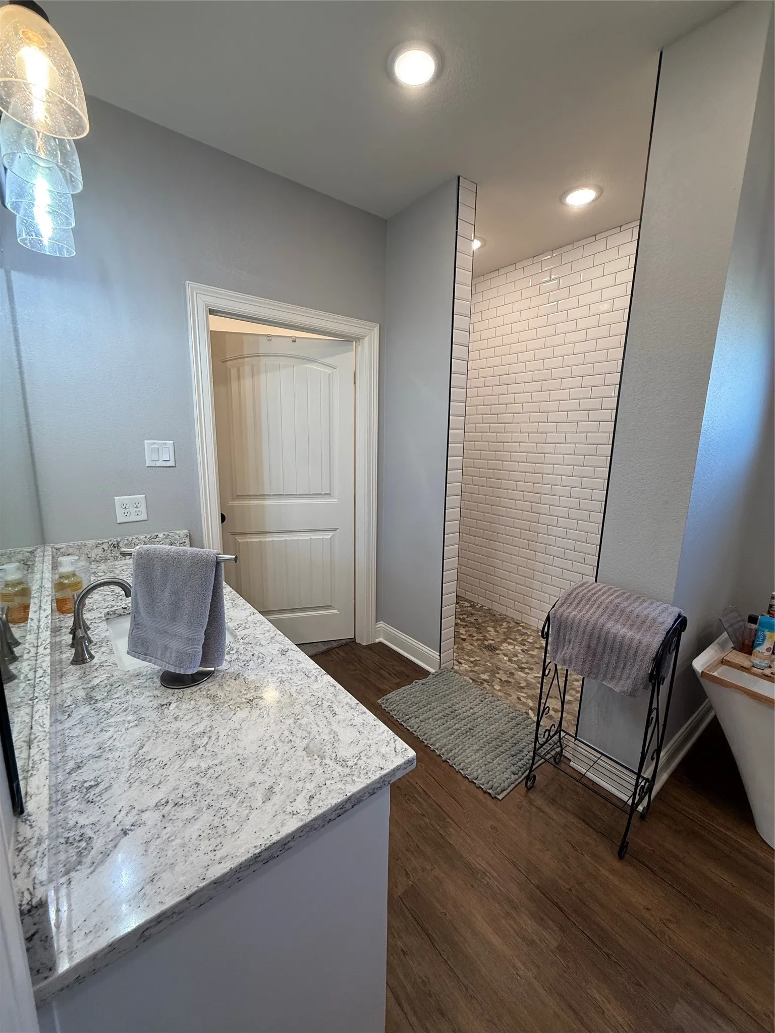 Bathroom featuring vanity, walk in shower, wood finished floors, recessed lighting, and baseboards