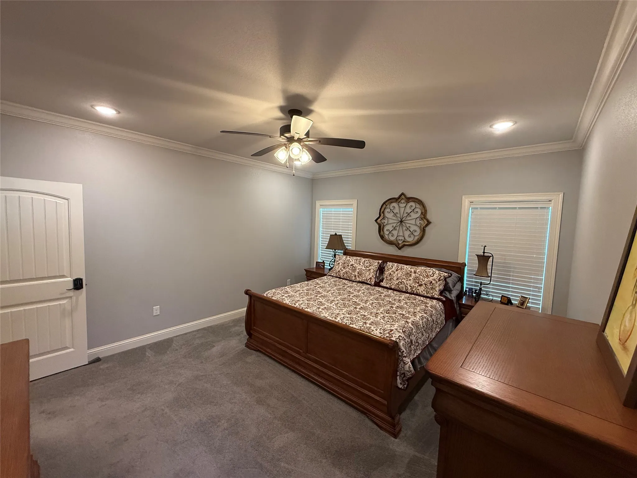 Carpeted bedroom featuring ornamental molding, a ceiling fan, and baseboards