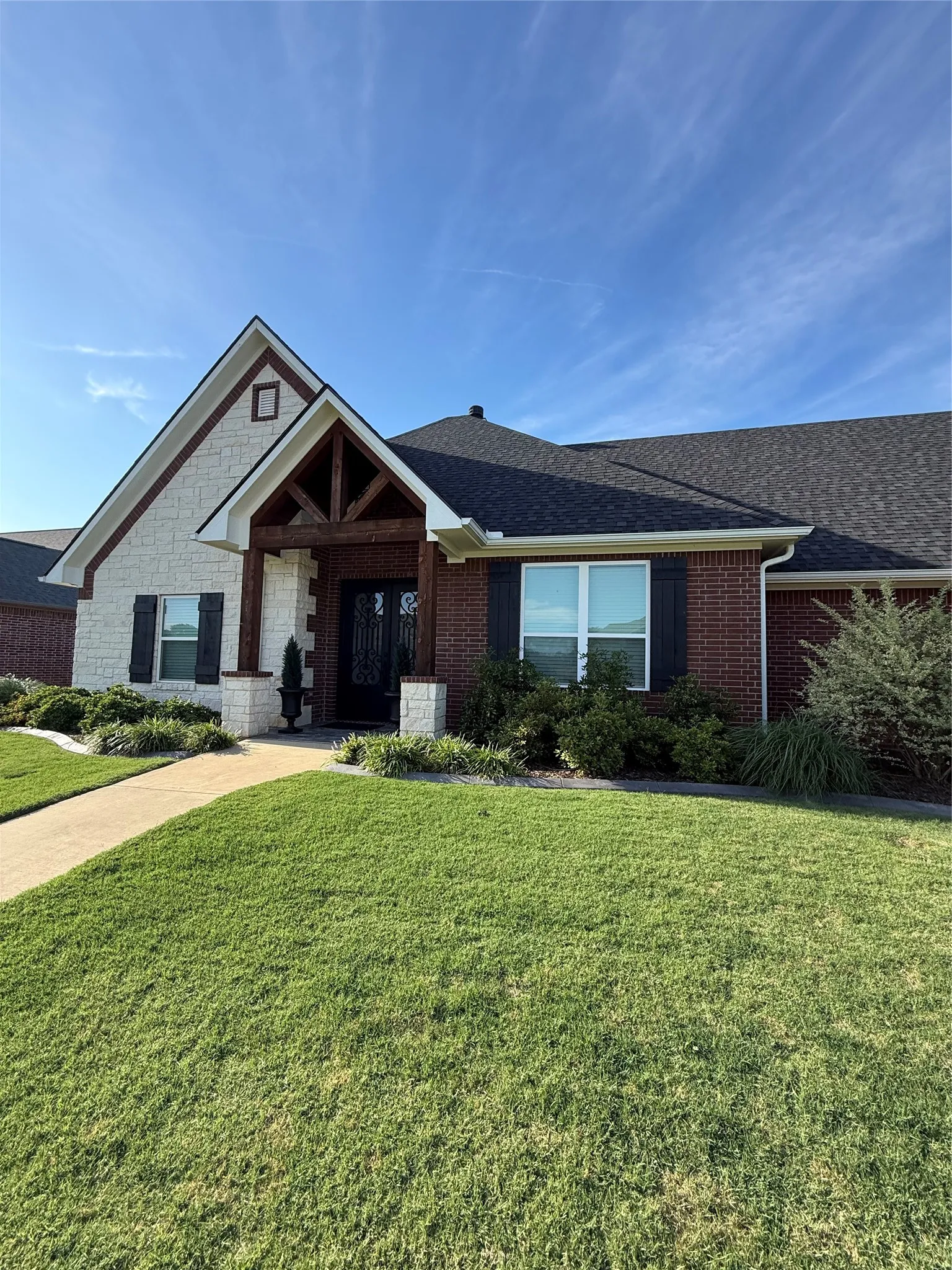 Ranch-style house with a front lawn, roof with shingles, and brick siding