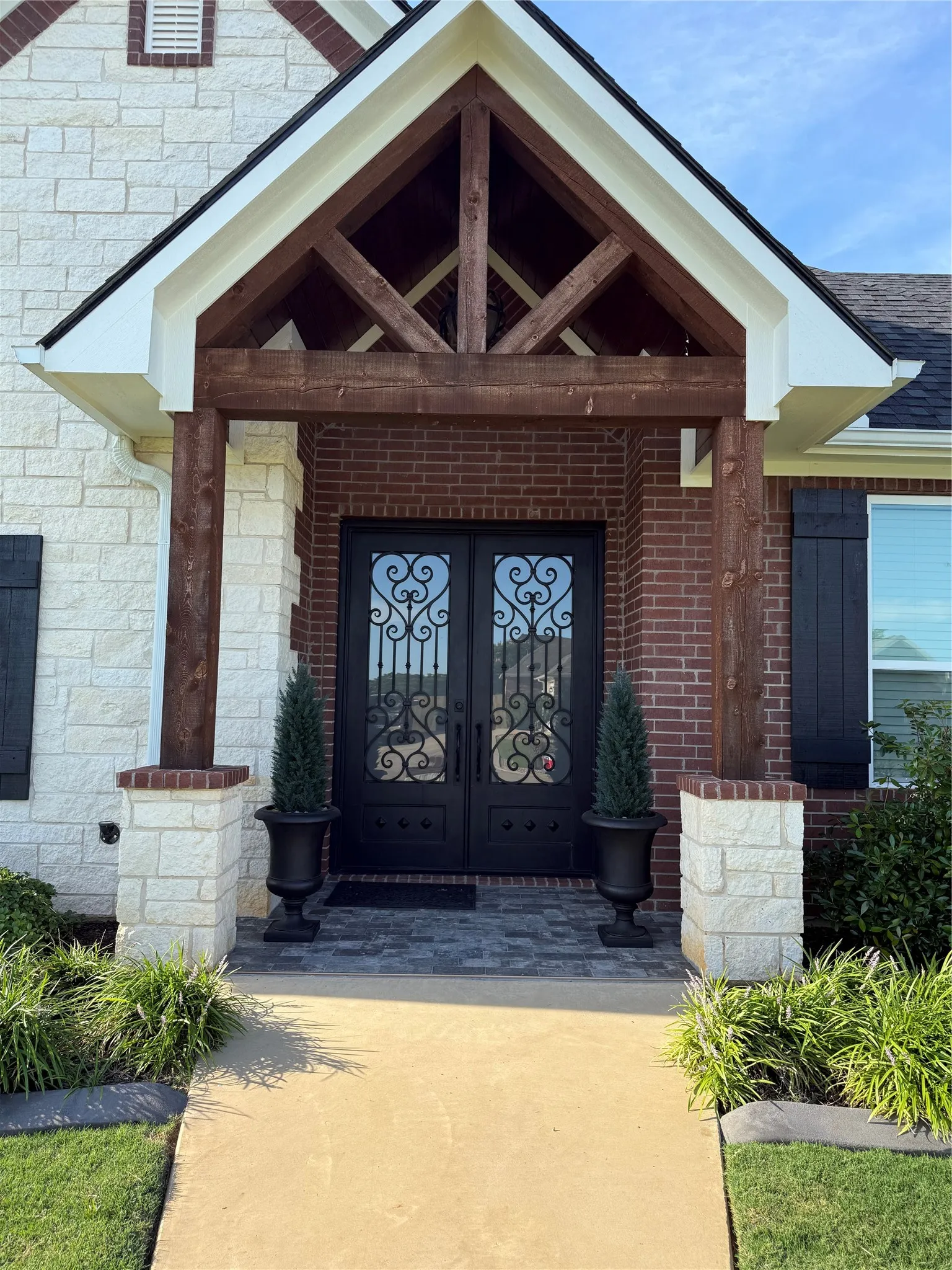 Doorway to property with french doors, stone siding, and roof with shingles