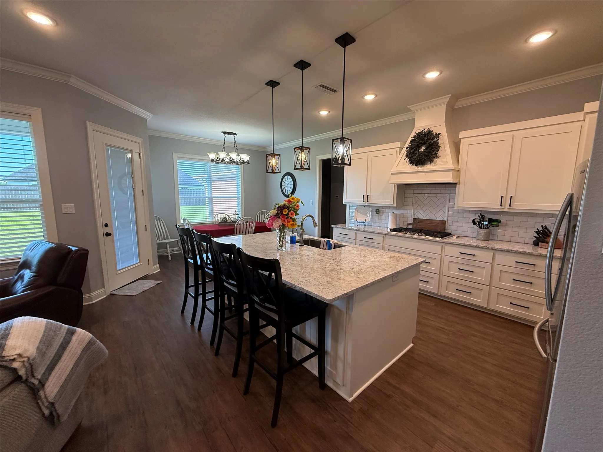 Kitchen with custom range hood, stainless steel appliances, a sink, dark wood-type flooring, and a breakfast bar area