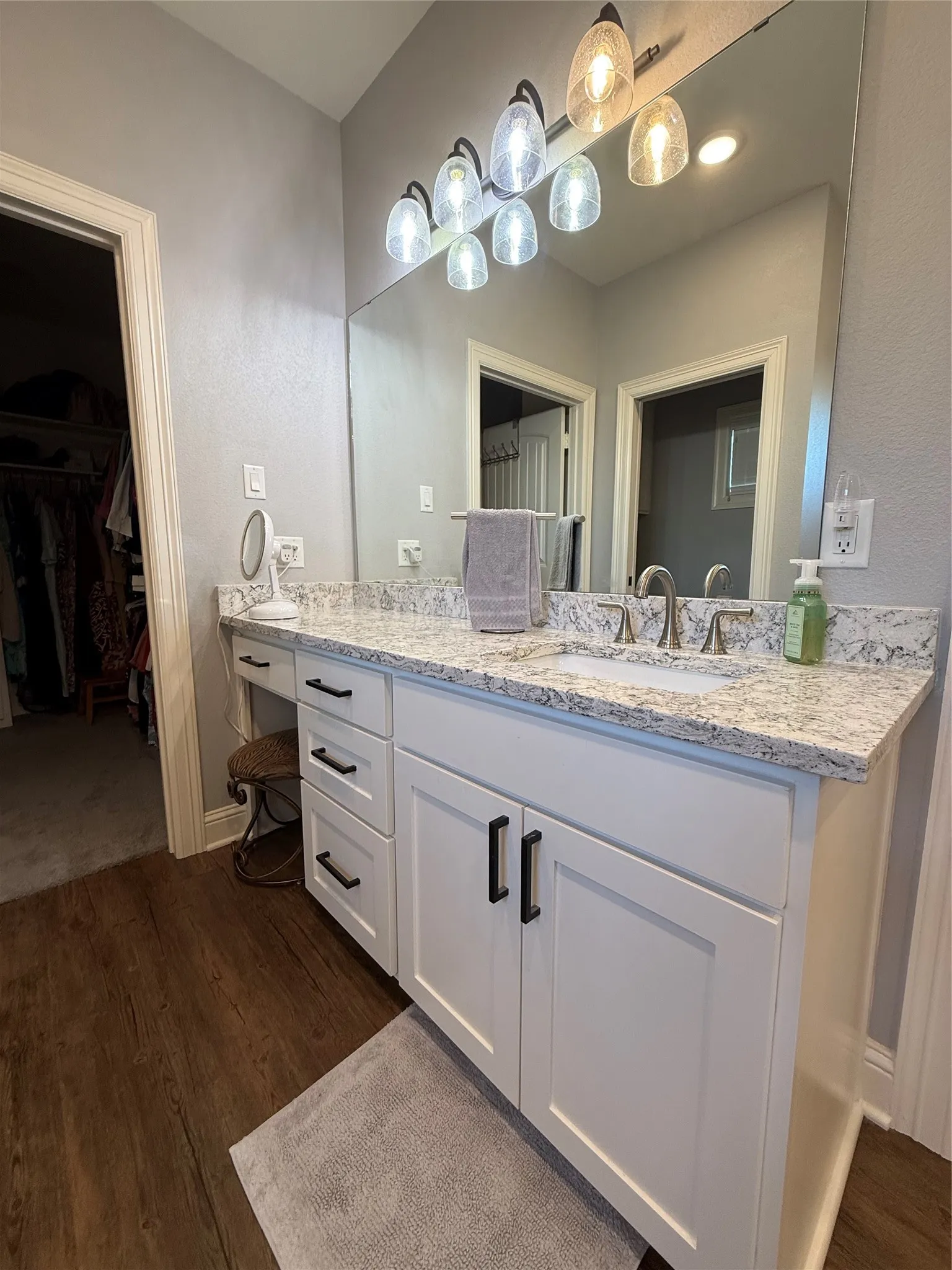 Full bathroom featuring vanity, wood finished floors, a spacious closet, and baseboards