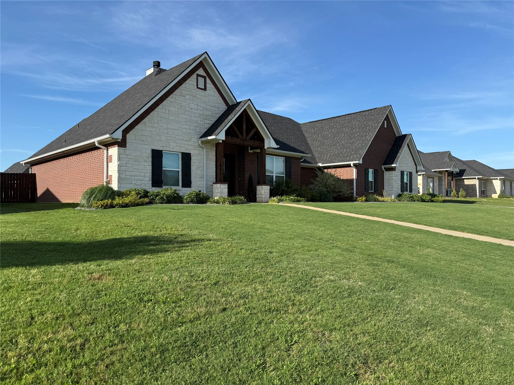 Craftsman-style house with a front lawn, stone siding, a chimney, and a shingled roof