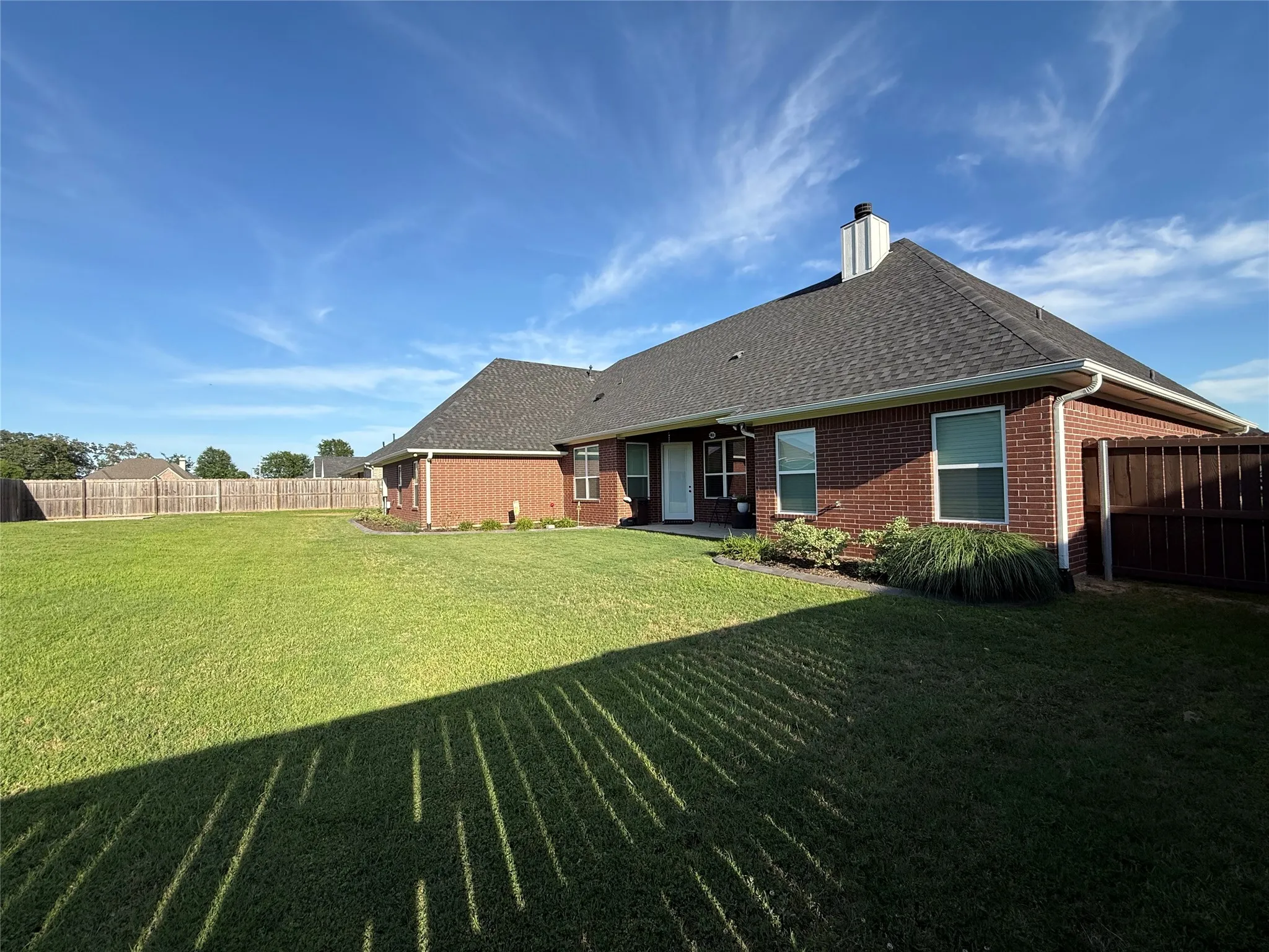 Back of property with brick siding, roof with shingles, and a chimney