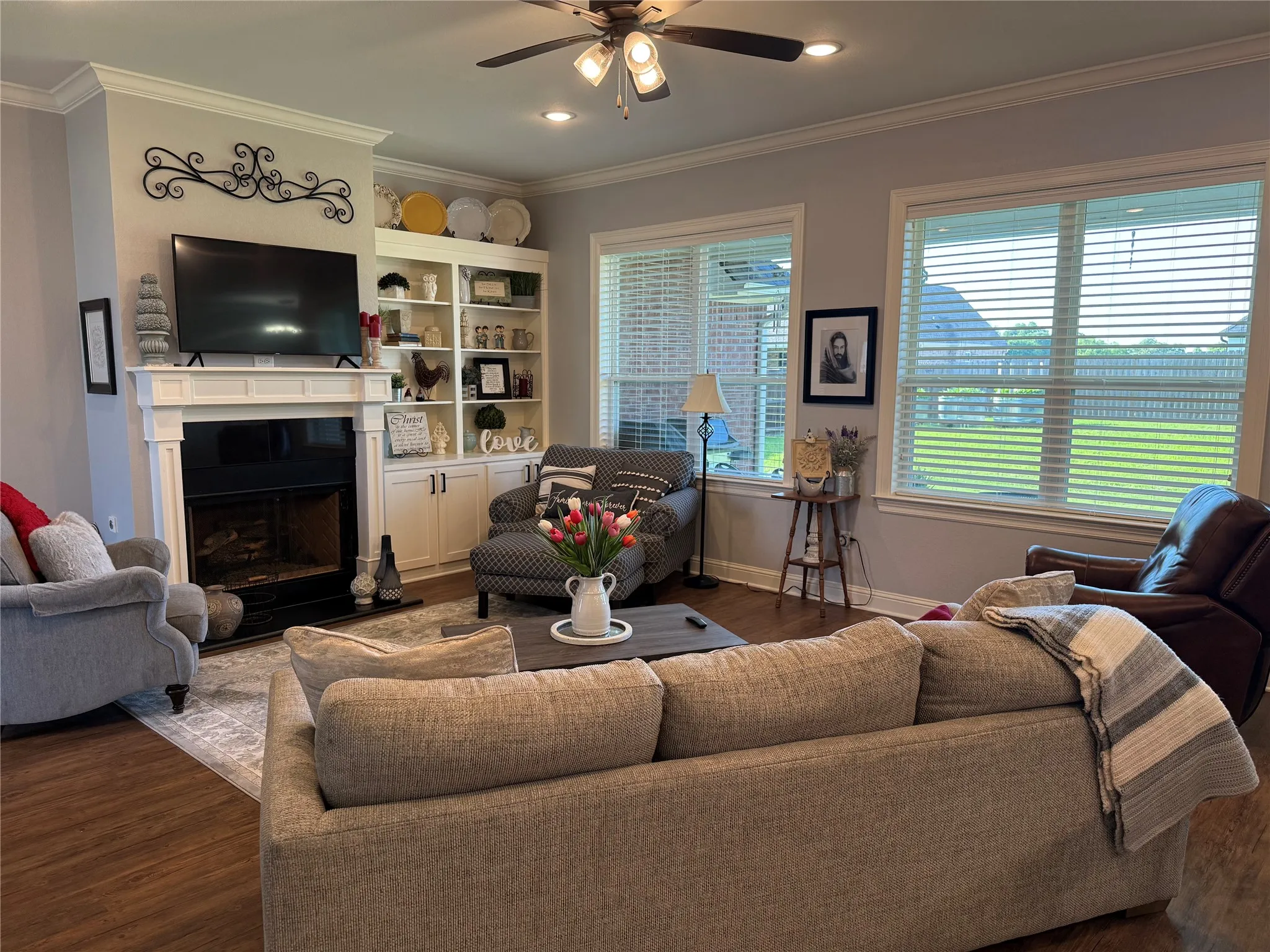Living area featuring dark wood-style floors, a ceiling fan, crown molding, a fireplace, and baseboards