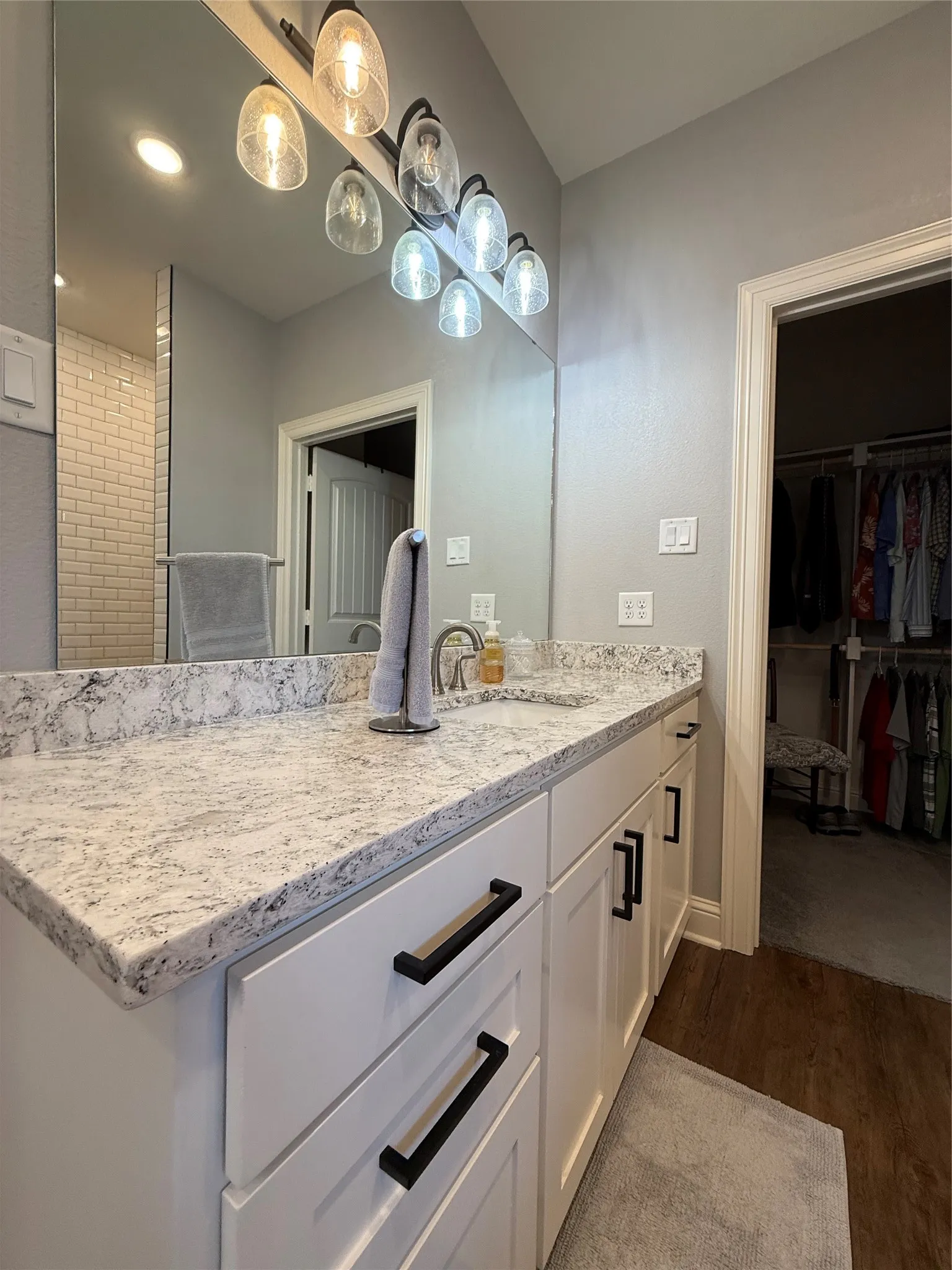 Bathroom featuring wood finished floors, vanity, a spacious closet, and baseboards