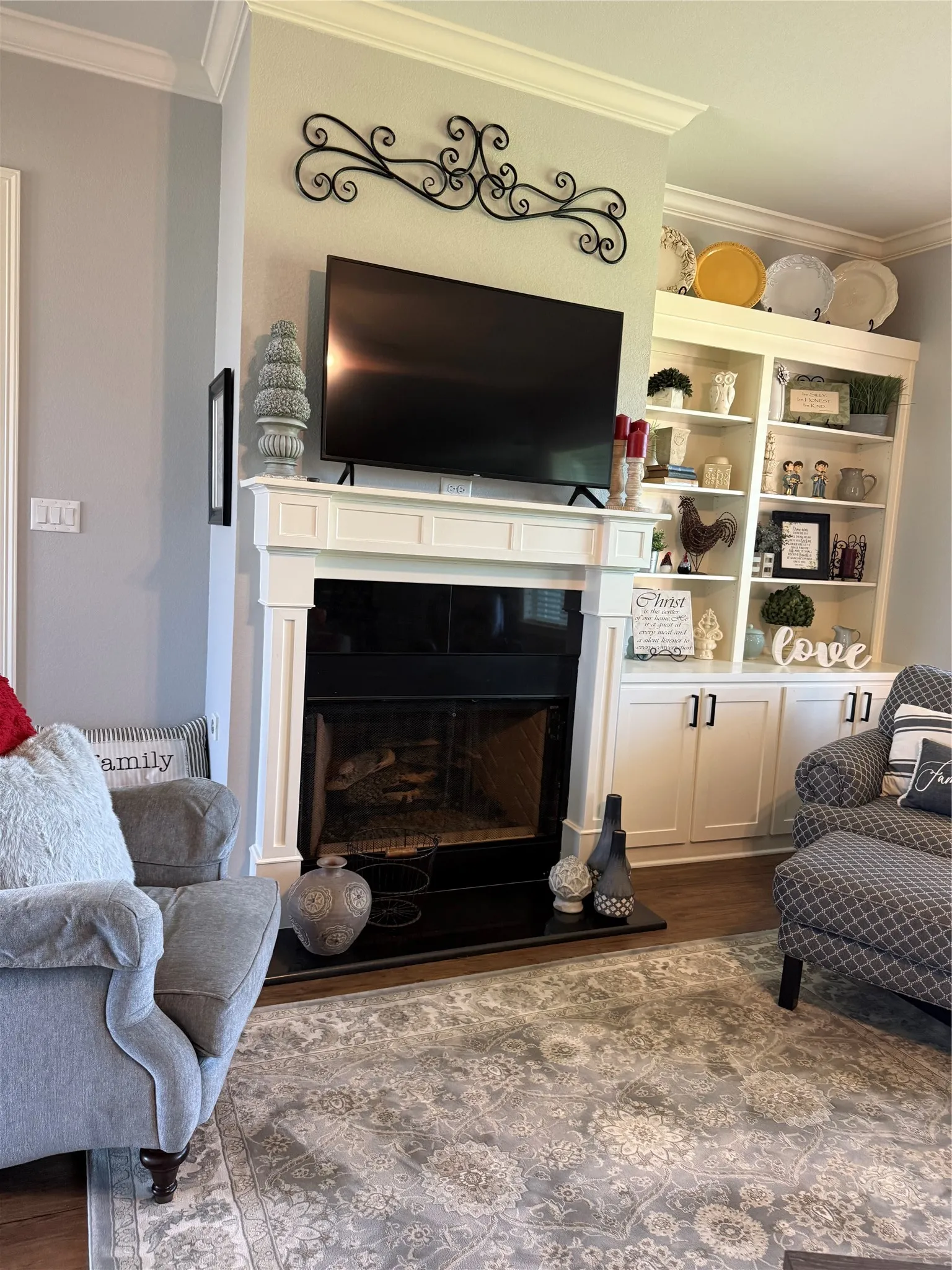Living room featuring ornamental molding, dark wood-type flooring, and a fireplace with raised hearth
