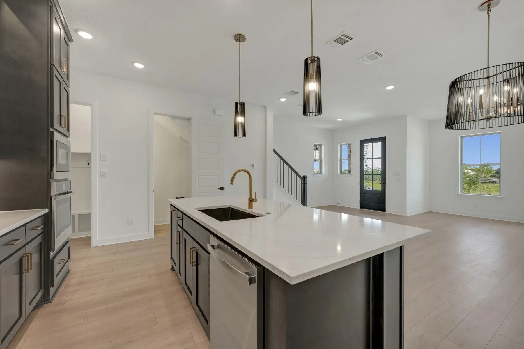 Contemporary kitchen featuring a large island with white stone countertop, integrated sink, and bronze-finish faucet