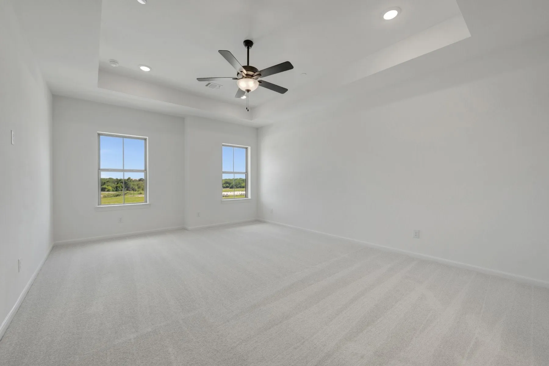 Spacious room featuring light-colored carpeting and white walls