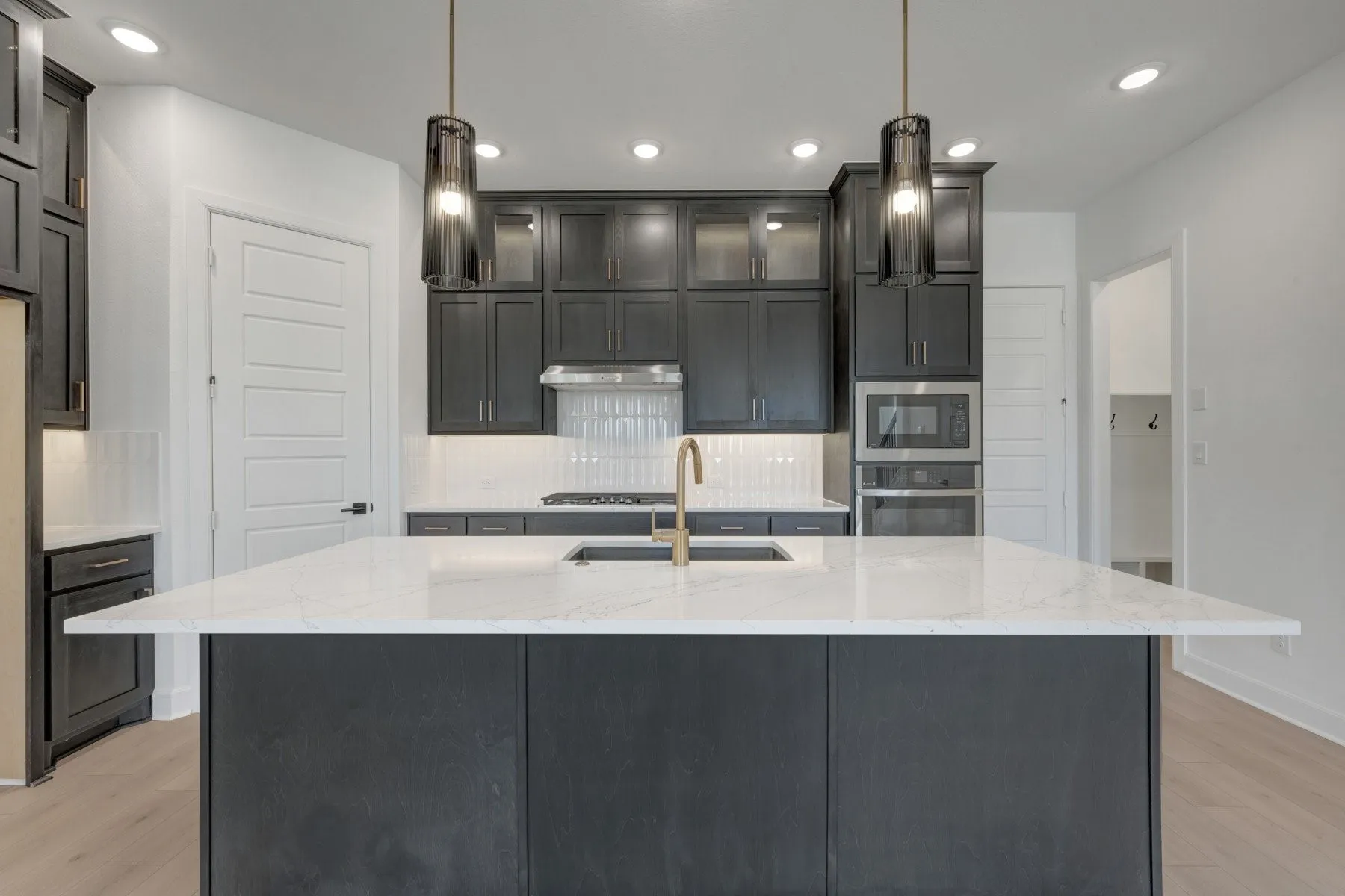 Kitchen featuring dark cabinetry, a large center island with a white stone countertop, a gold-finish faucet, and stainless steel appliances