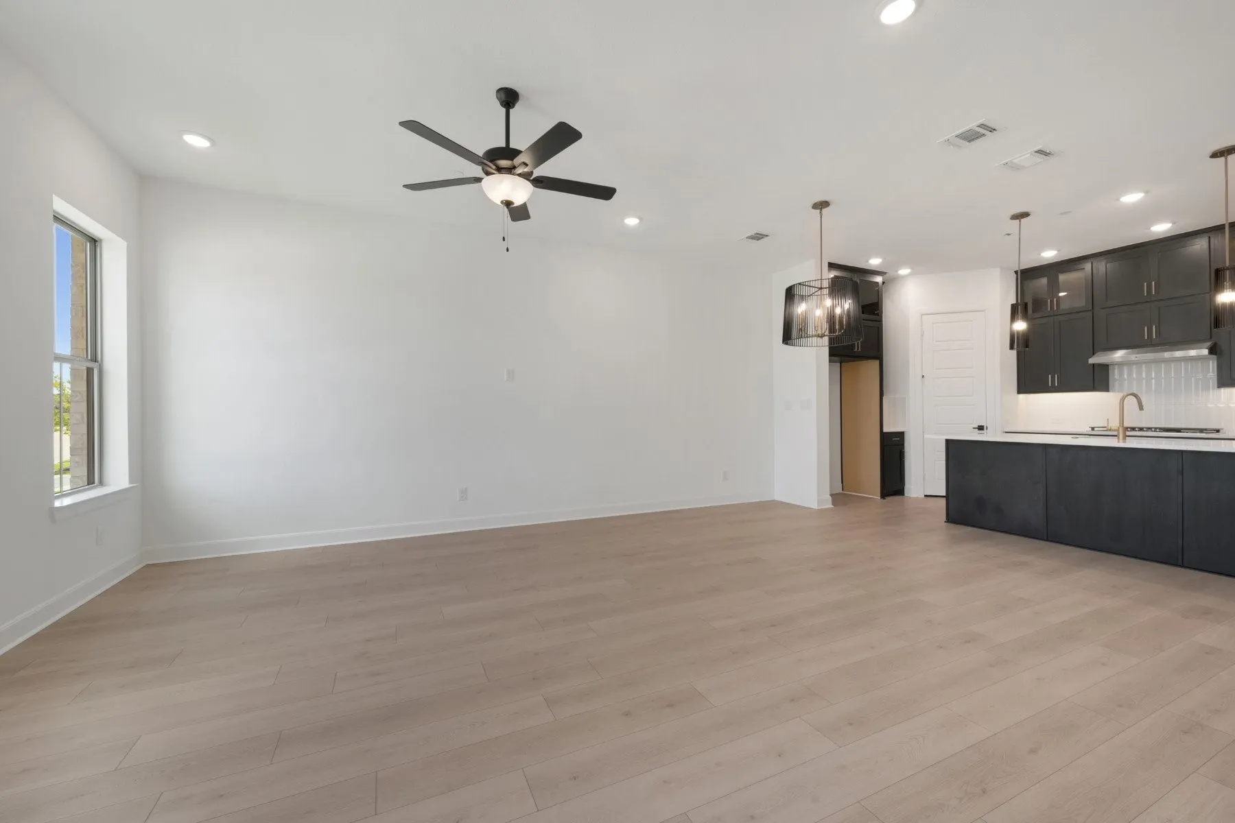 Expansive room featuring light wood-finish flooring and recessed lighting
