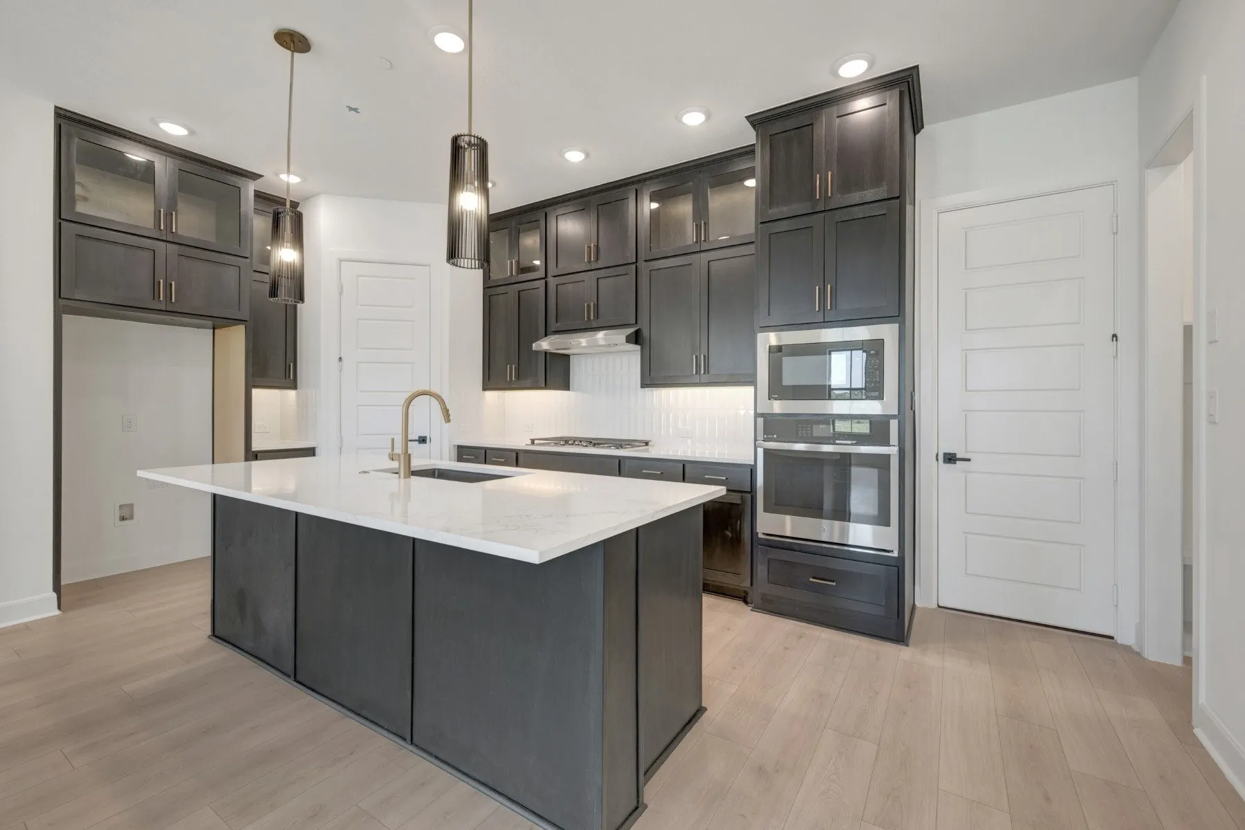 Kitchen featuring a spacious island with a white countertop, dark cabinetry, stainless steel appliances, and wood-finish flooring