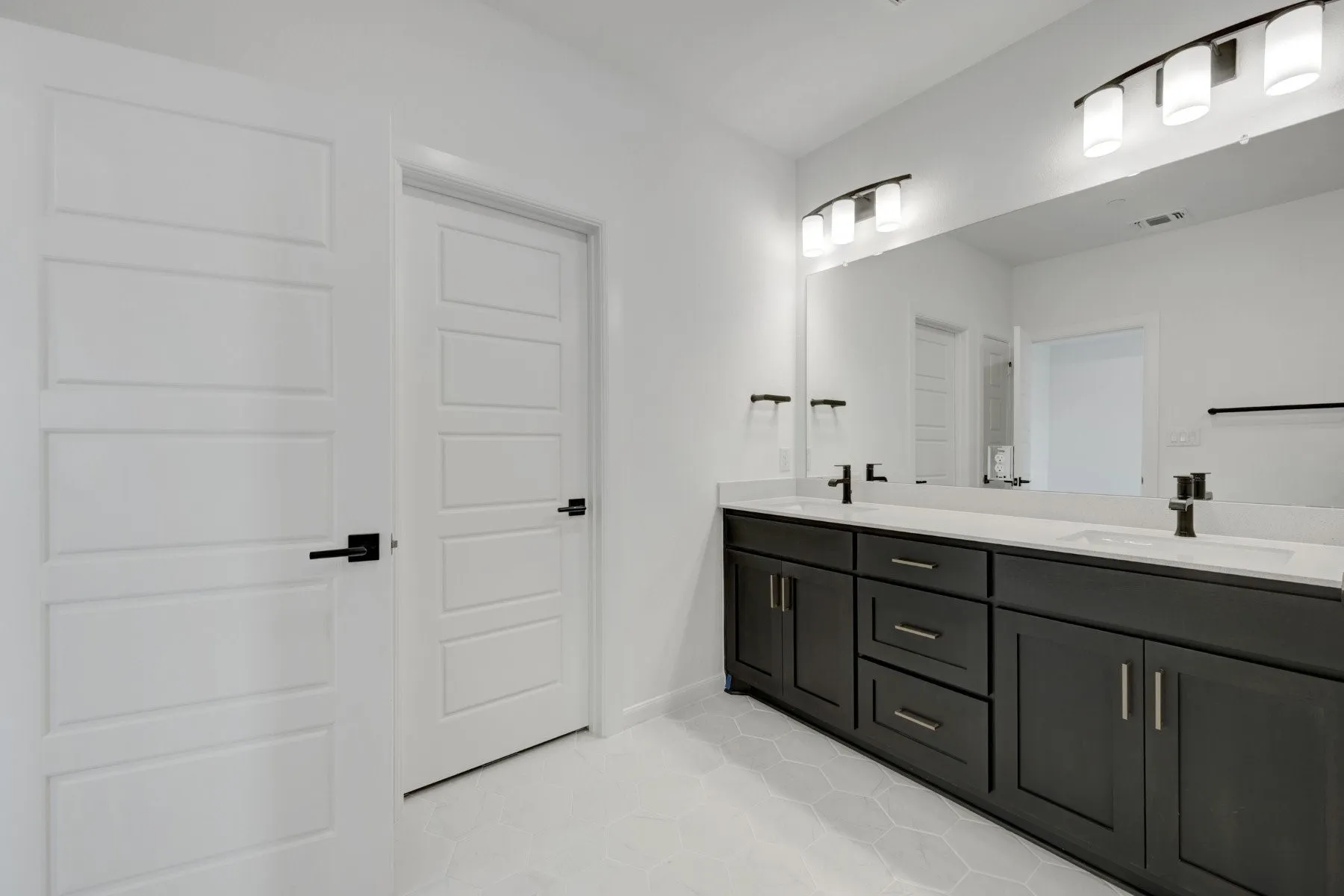Dual vanity with dark wood cabinetry, white countertops, and matte black fixtures